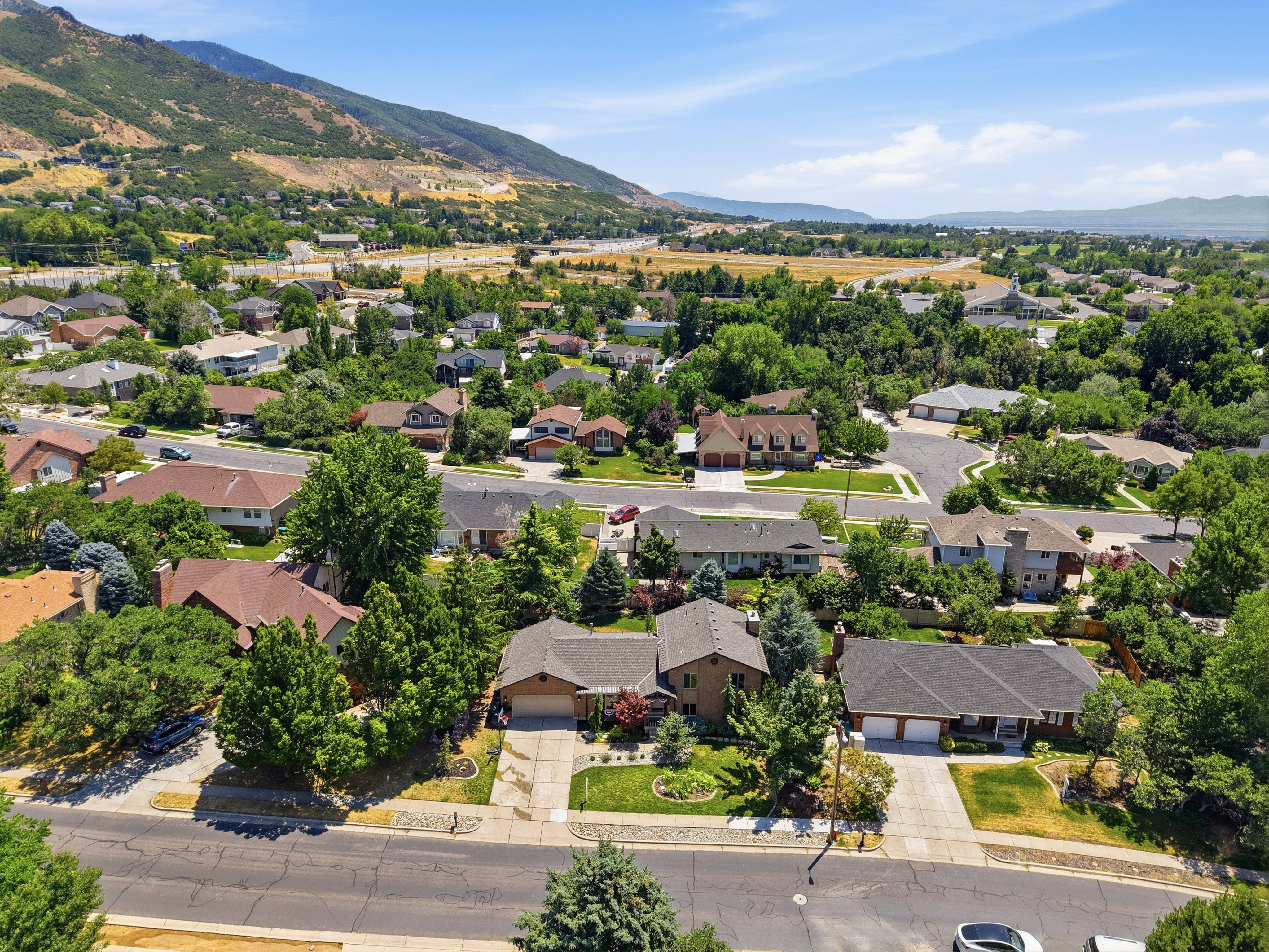 Residential neighborhood with mature trees, established homes, and mountain backdrop