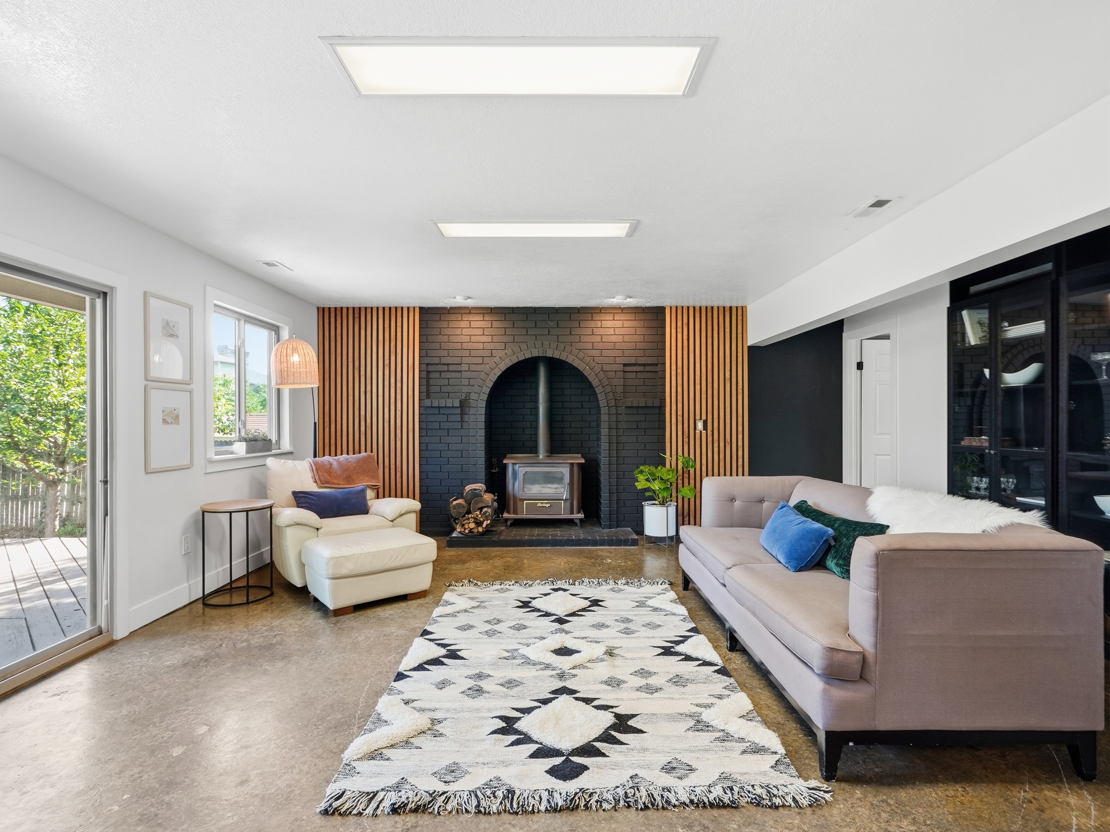Spacious living area featuring a wood-burning stove with a brick surround, wood slat wall accents, and concrete flooring