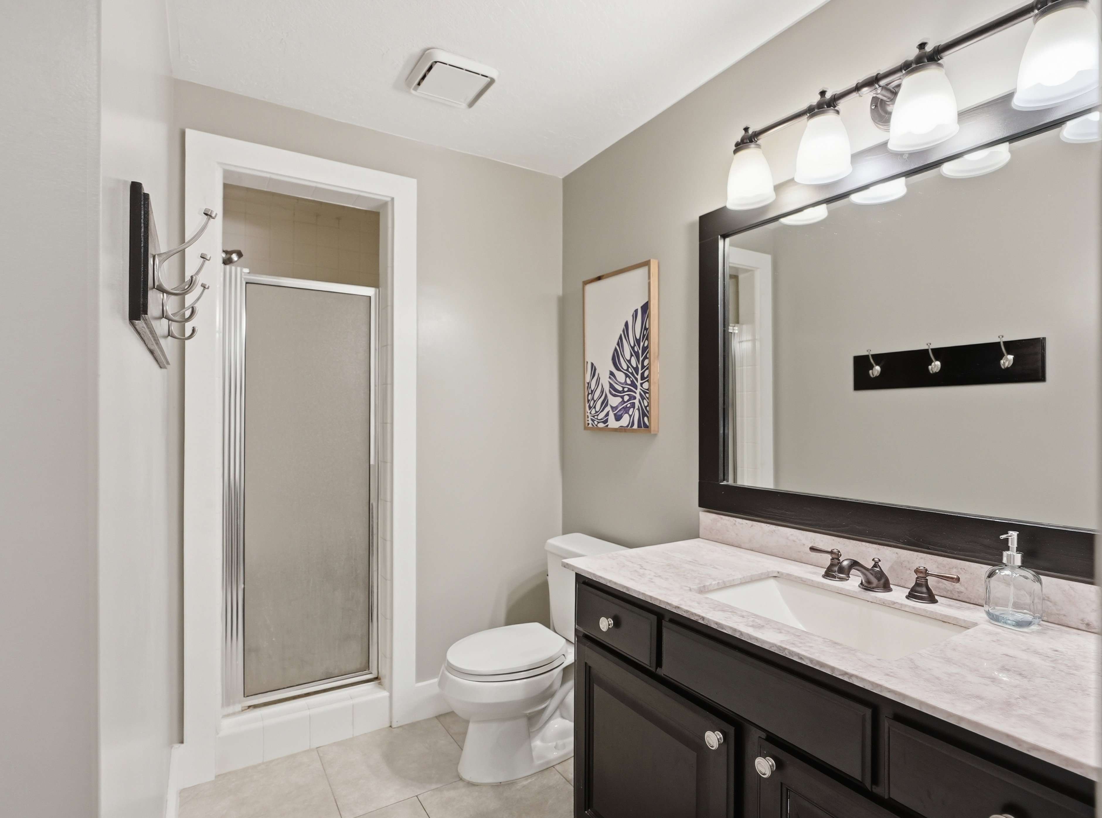 Bathroom featuring a dark wood vanity with a light-colored countertop, an integrated sink, and a framed mirror