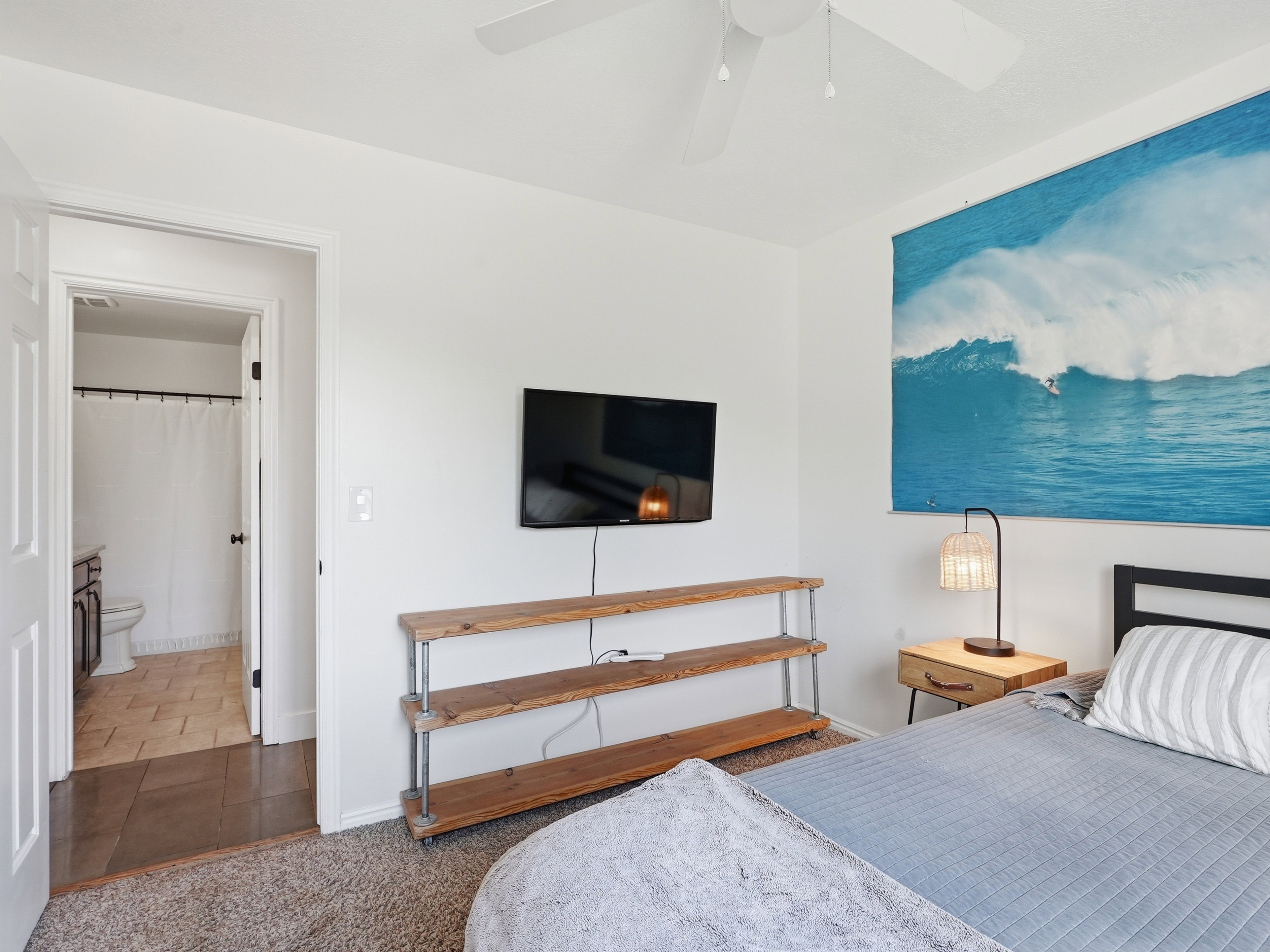 Bedroom featuring a ceiling fan, wall-mounted television, and a wood-finish shelving unit