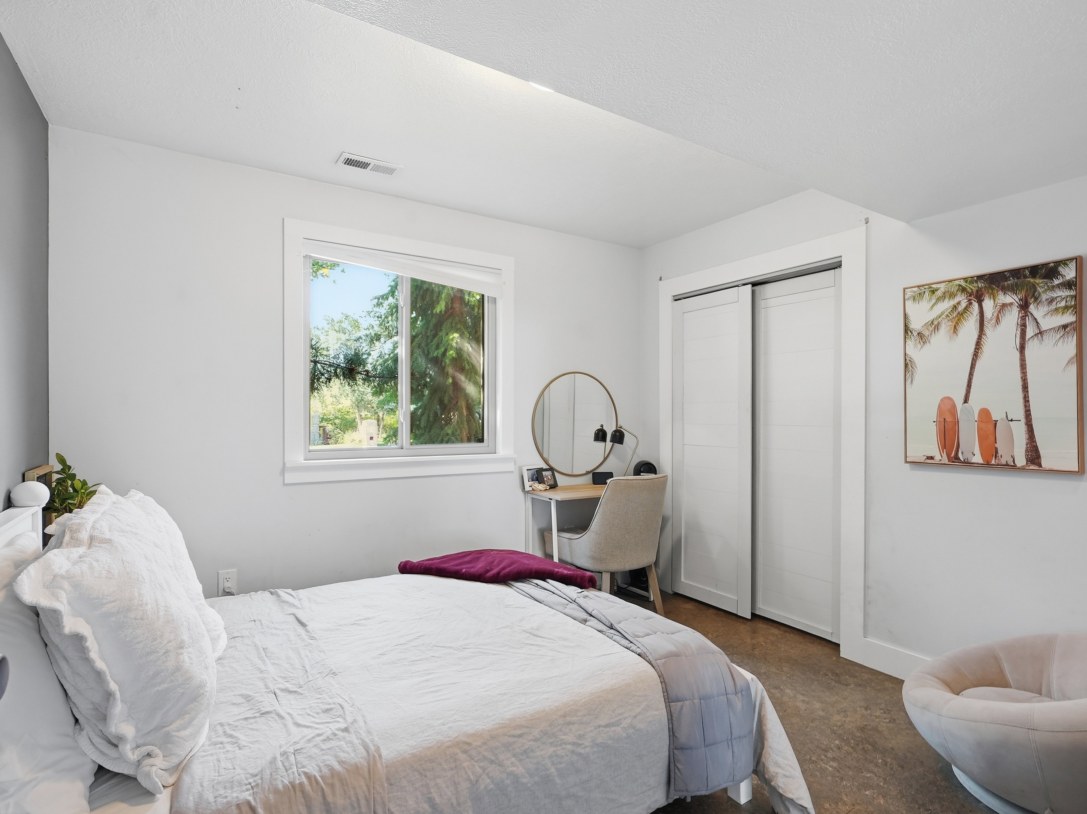 Bright bedroom featuring a large window, neutral wall tones, and wood-finish flooring