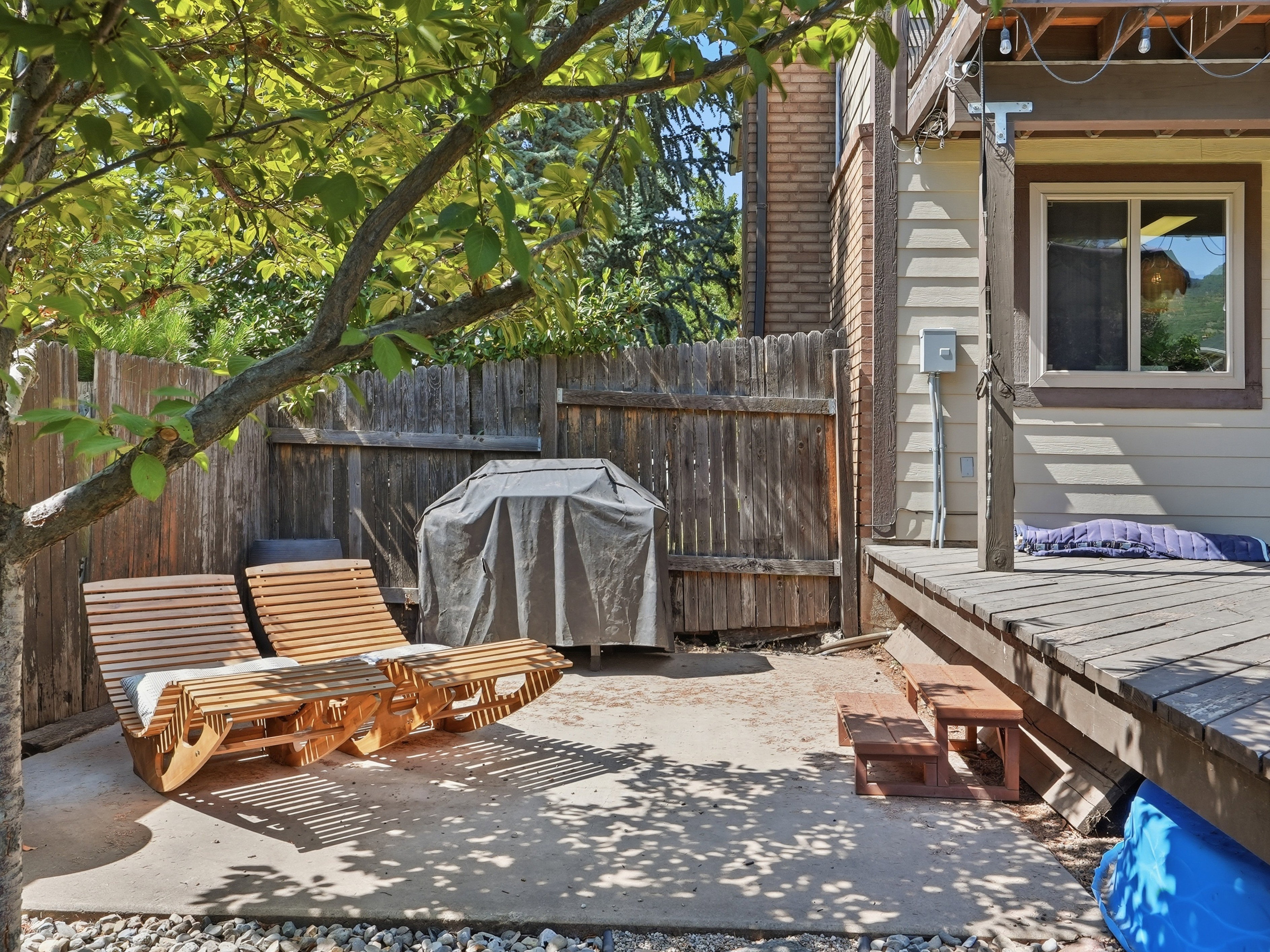 Outdoor patio area featuring a concrete pad, gravel border, and a wooden privacy fence