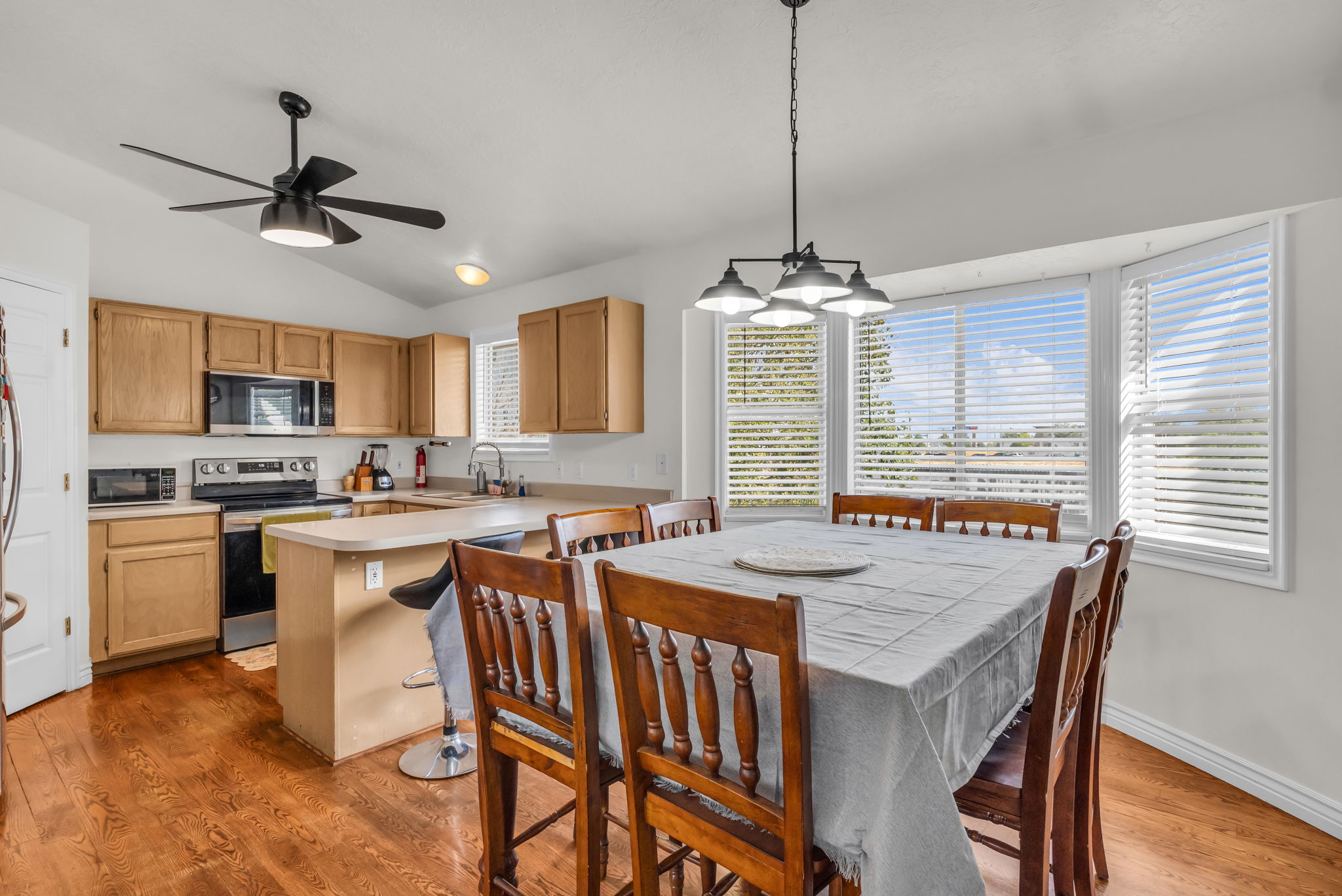 Kitchen and dining area featuring warm wood-finish flooring, a vaulted ceiling, and a bay window