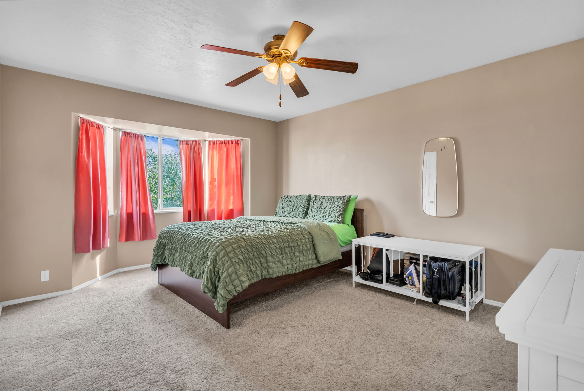 Bedroom featuring a bay window, ceiling fan with integrated lighting, and neutral carpeting