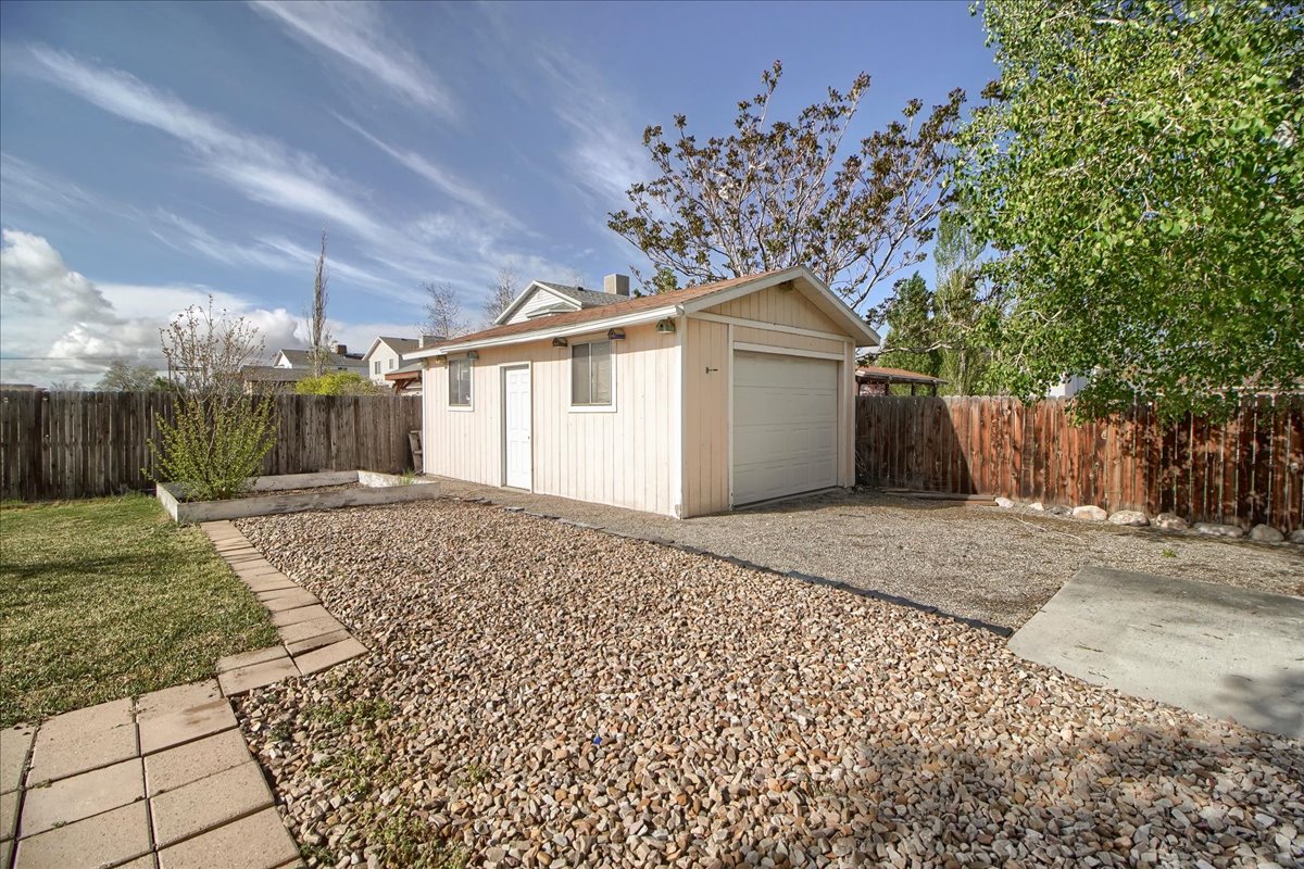 Detached single-car garage featuring vertical siding, an overhead door, and a separate entry door