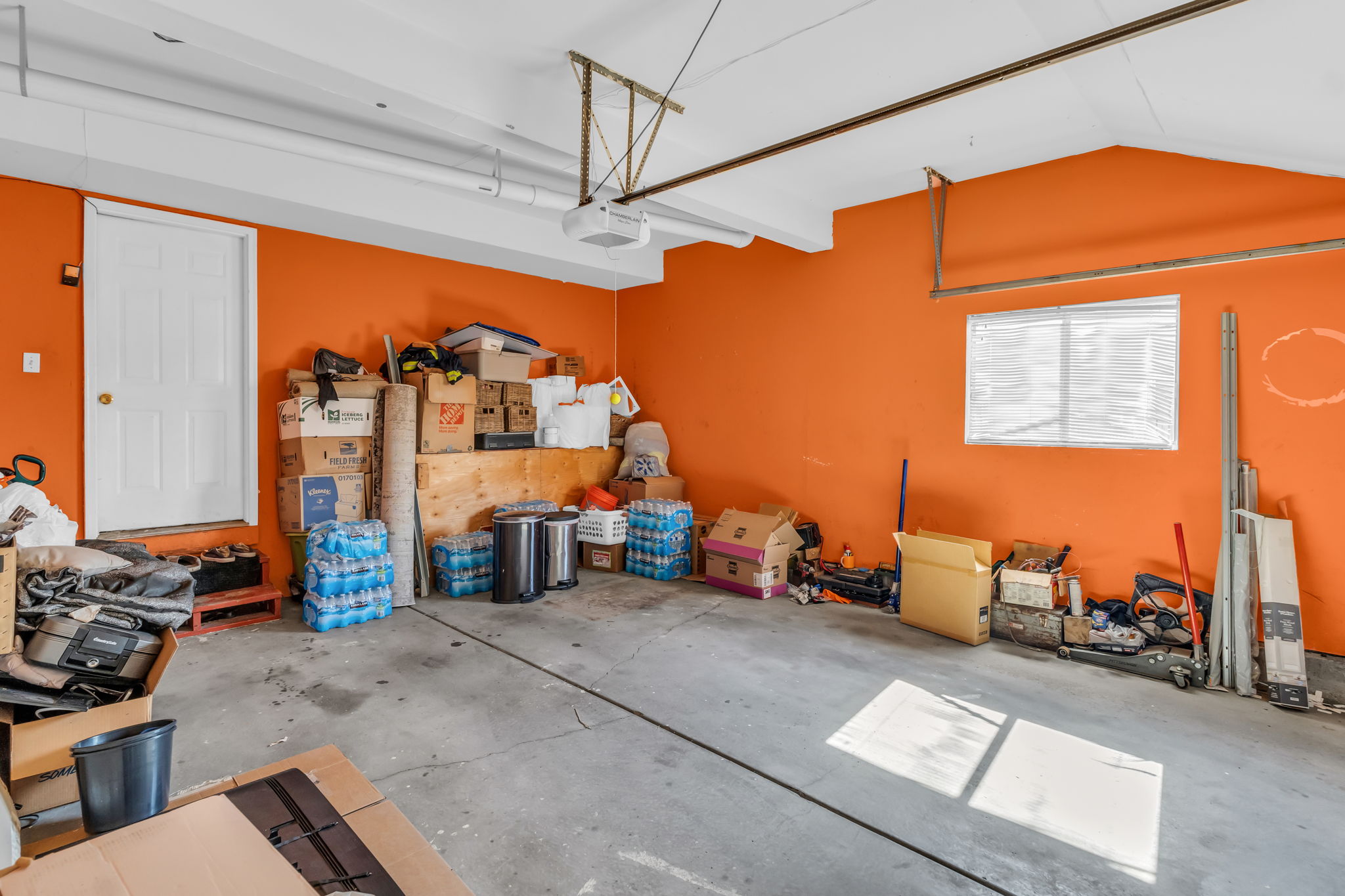 Spacious garage featuring concrete flooring, a side access door, and a window for natural light