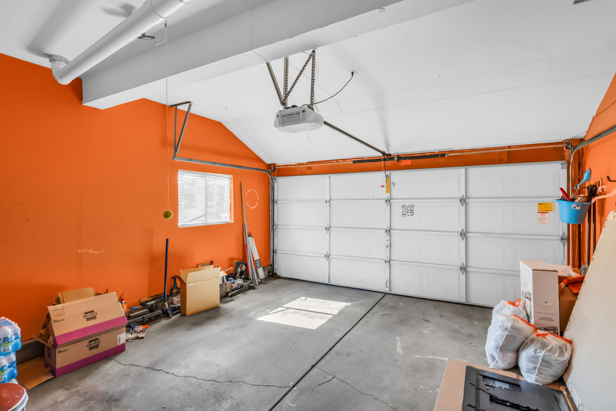 Attached garage featuring a concrete floor, an overhead garage door, and a single window