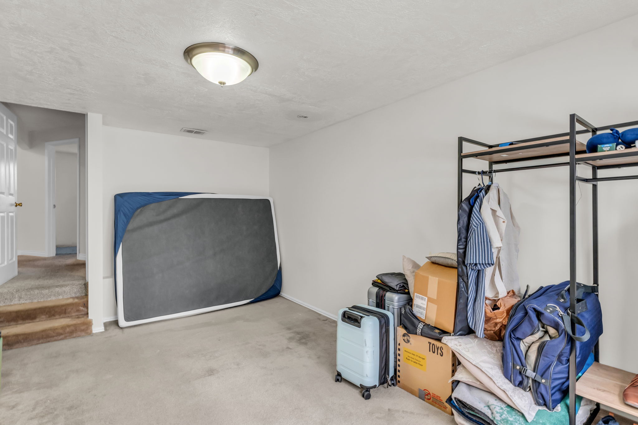 Carpeted room with a flush-mount ceiling light fixture, white walls, and a white interior door