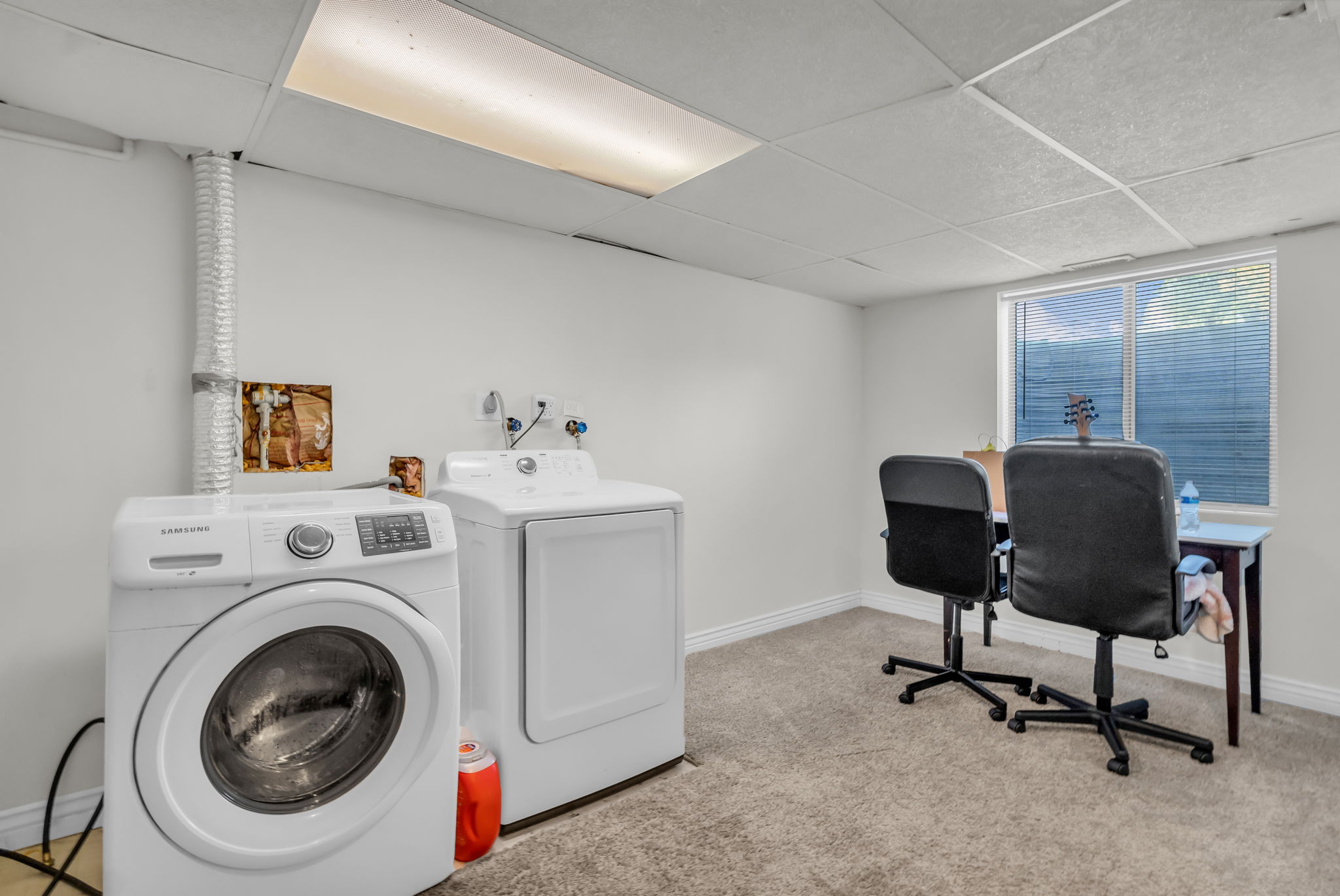 Laundry area featuring a drop ceiling, window, and wall-mounted plumbing for appliances