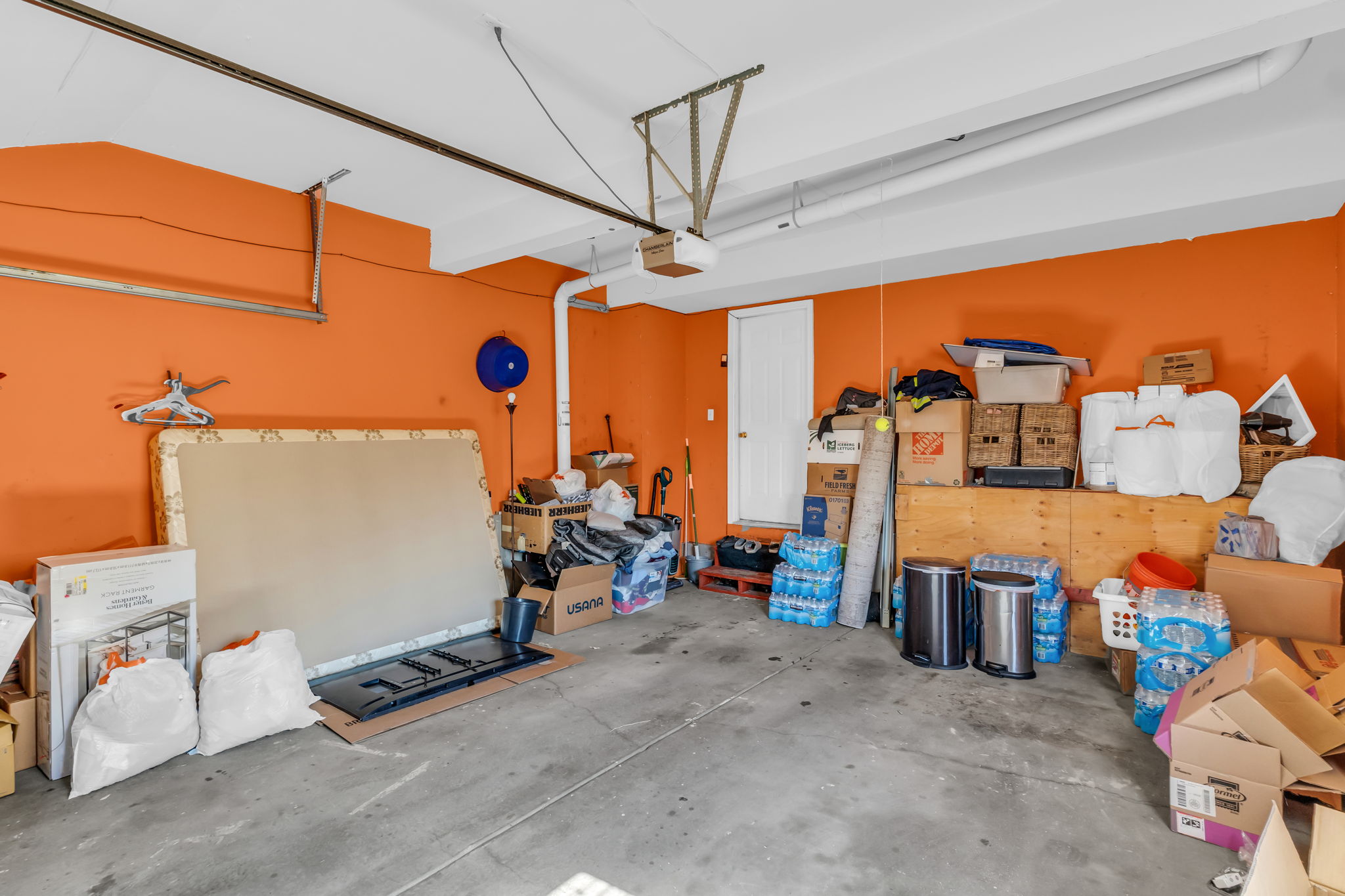 Spacious garage featuring a concrete floor, vibrant orange walls, and a white ceiling