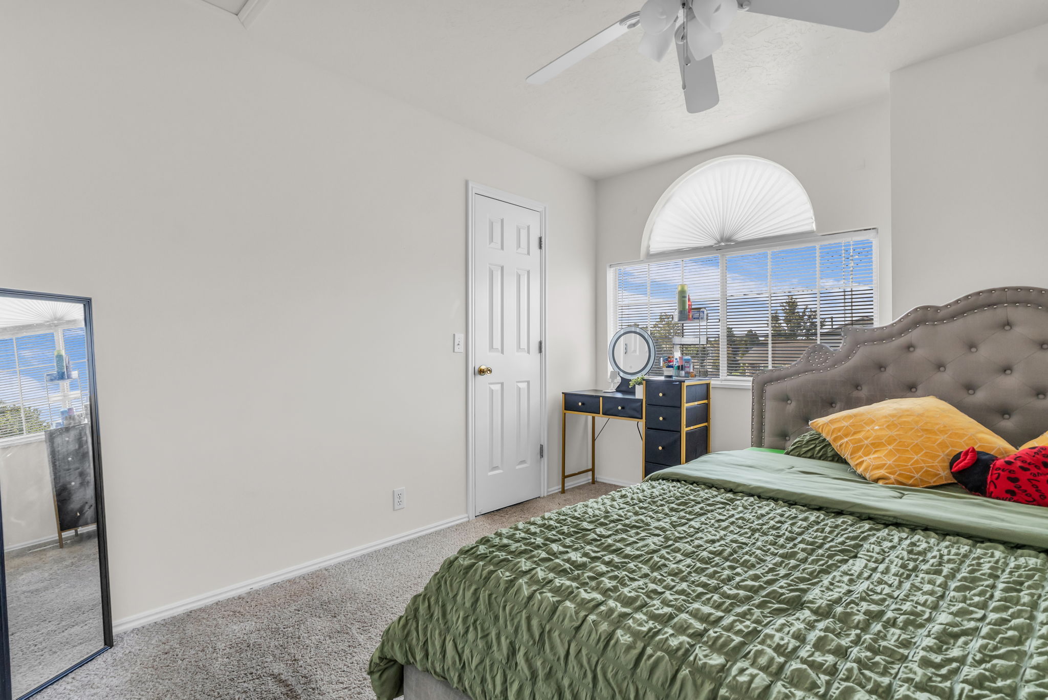 Room featuring a large window with an arched transom, a ceiling fan, and carpeted flooring