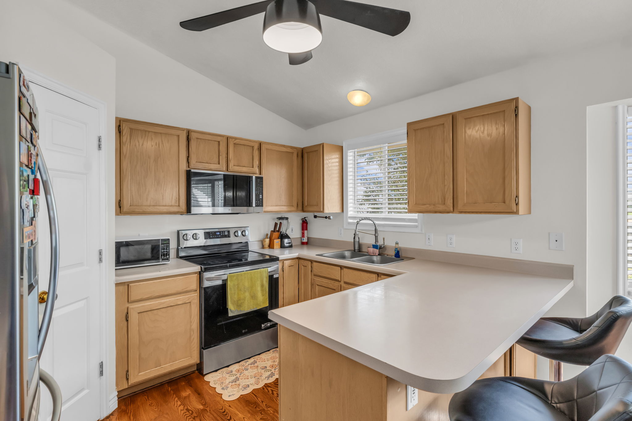 Kitchen featuring wood-finish cabinetry, light-toned countertops, and a double basin sink with a gooseneck faucet