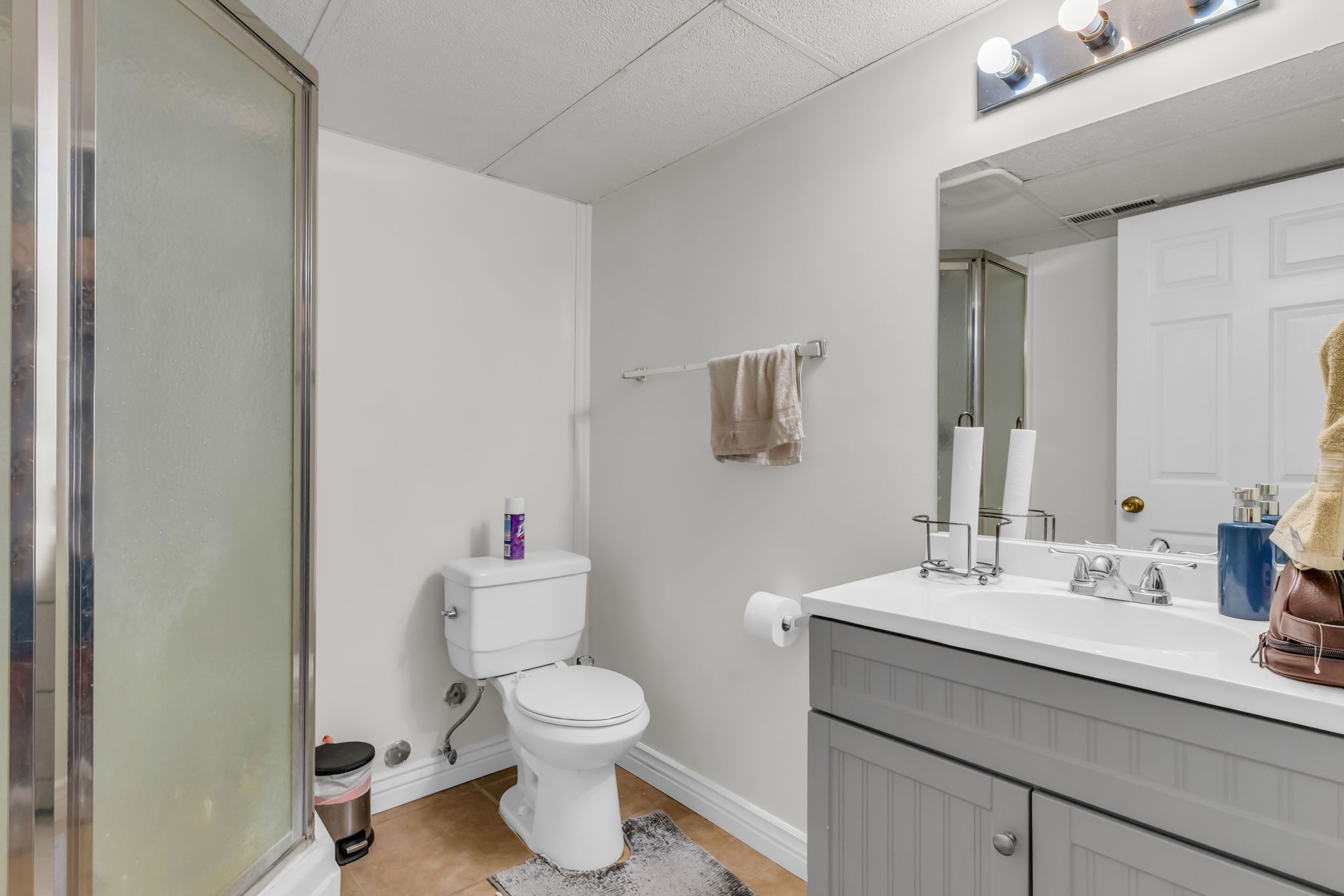 Bathroom featuring a glass-enclosed shower, a vanity with a white countertop, and a built-in sink