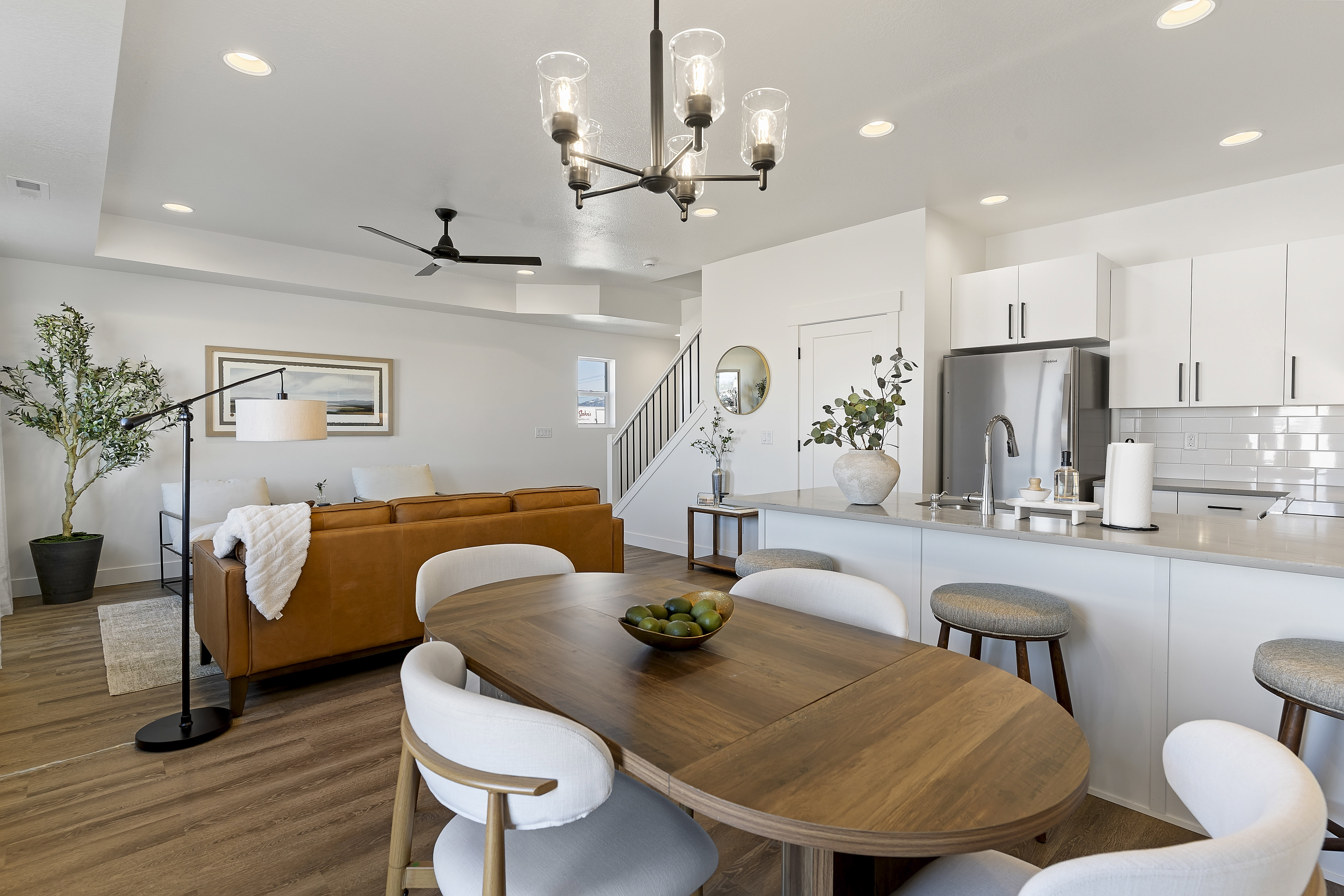 Open-concept living space featuring wood-finish flooring, recessed lighting, and a modern kitchen with a white subway tile backsplash and stainless steel appliances