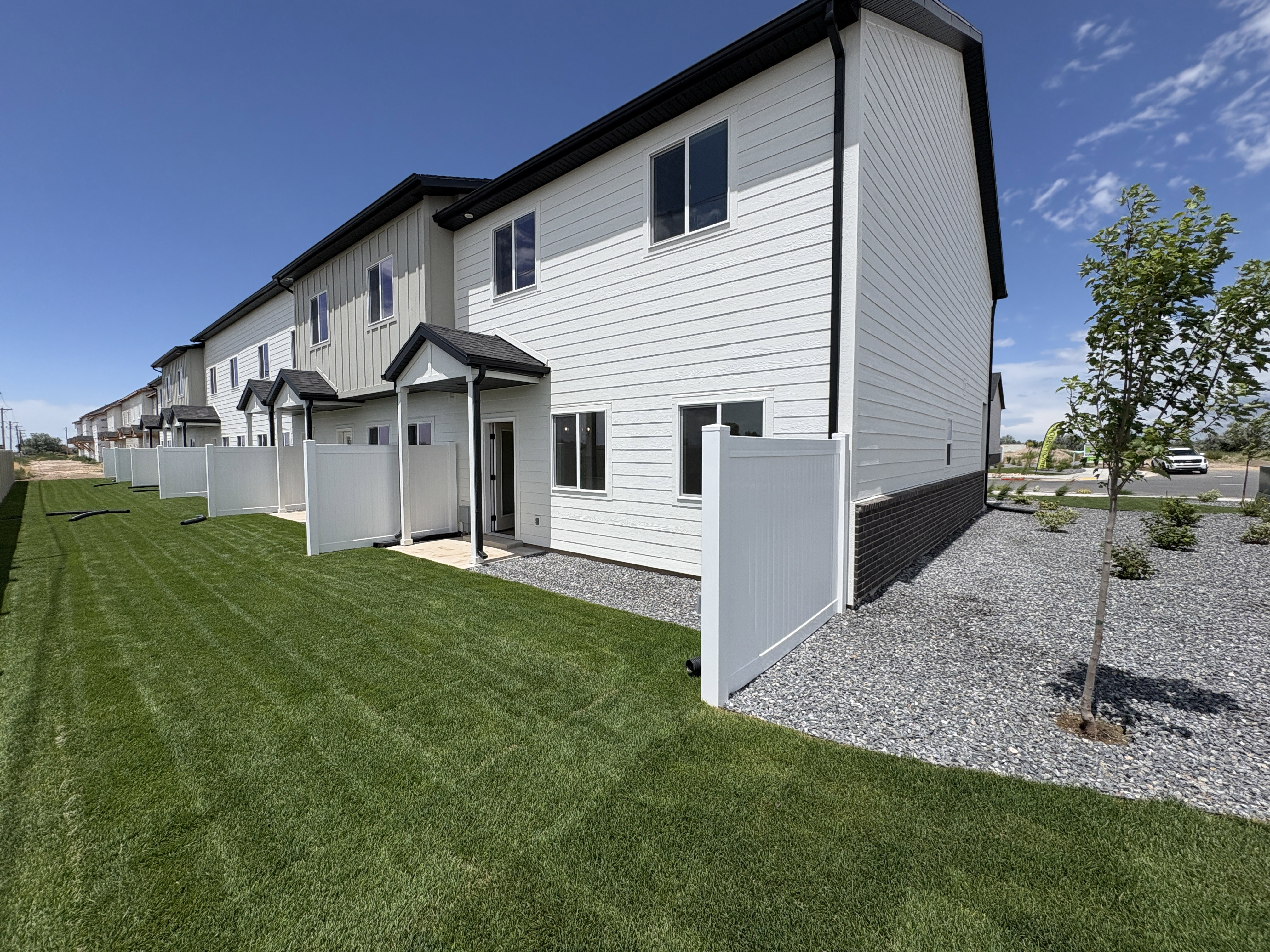 Contemporary townhome exterior featuring white siding, black trim, and a covered entry