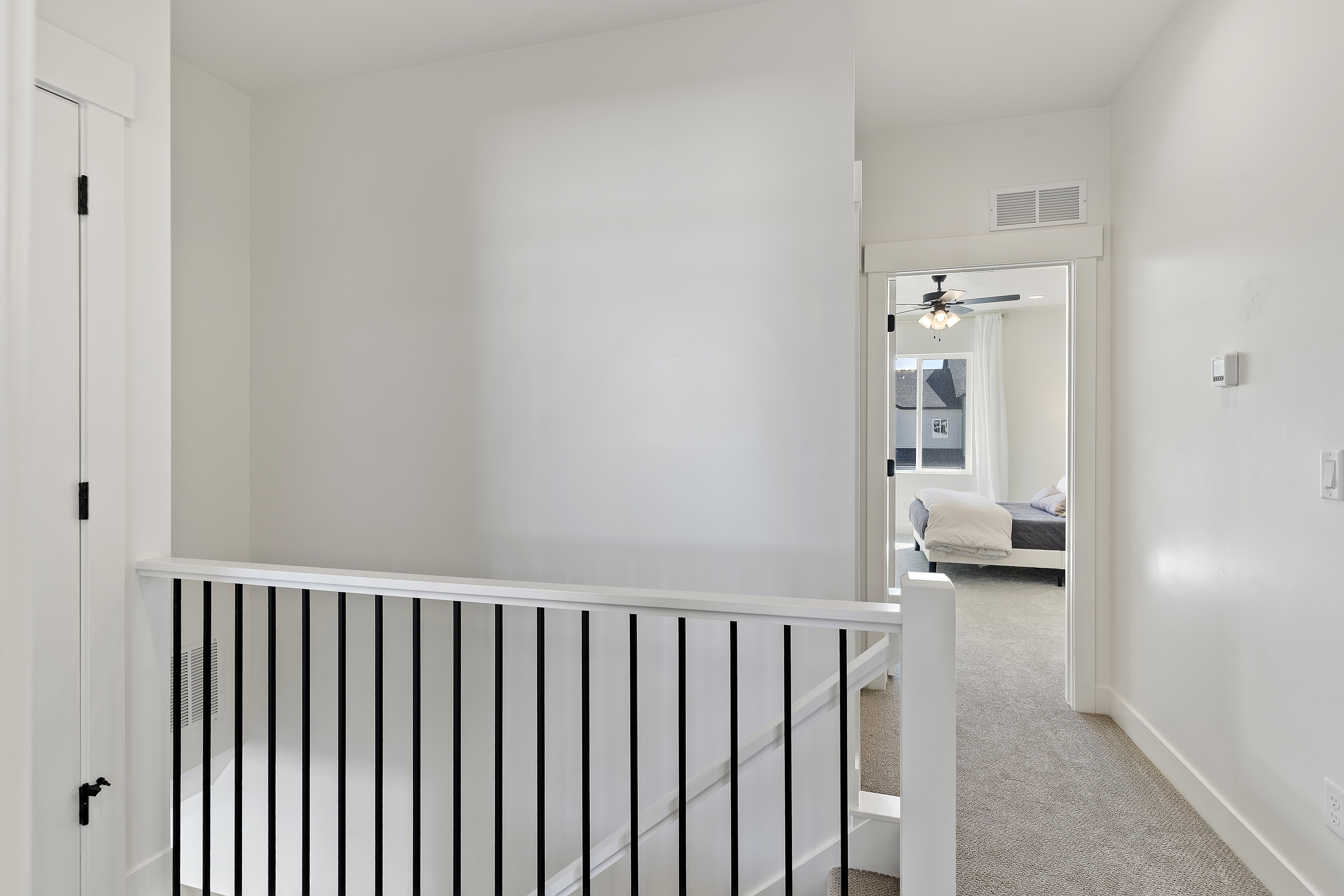 Upper-level hallway with carpeted flooring and white walls