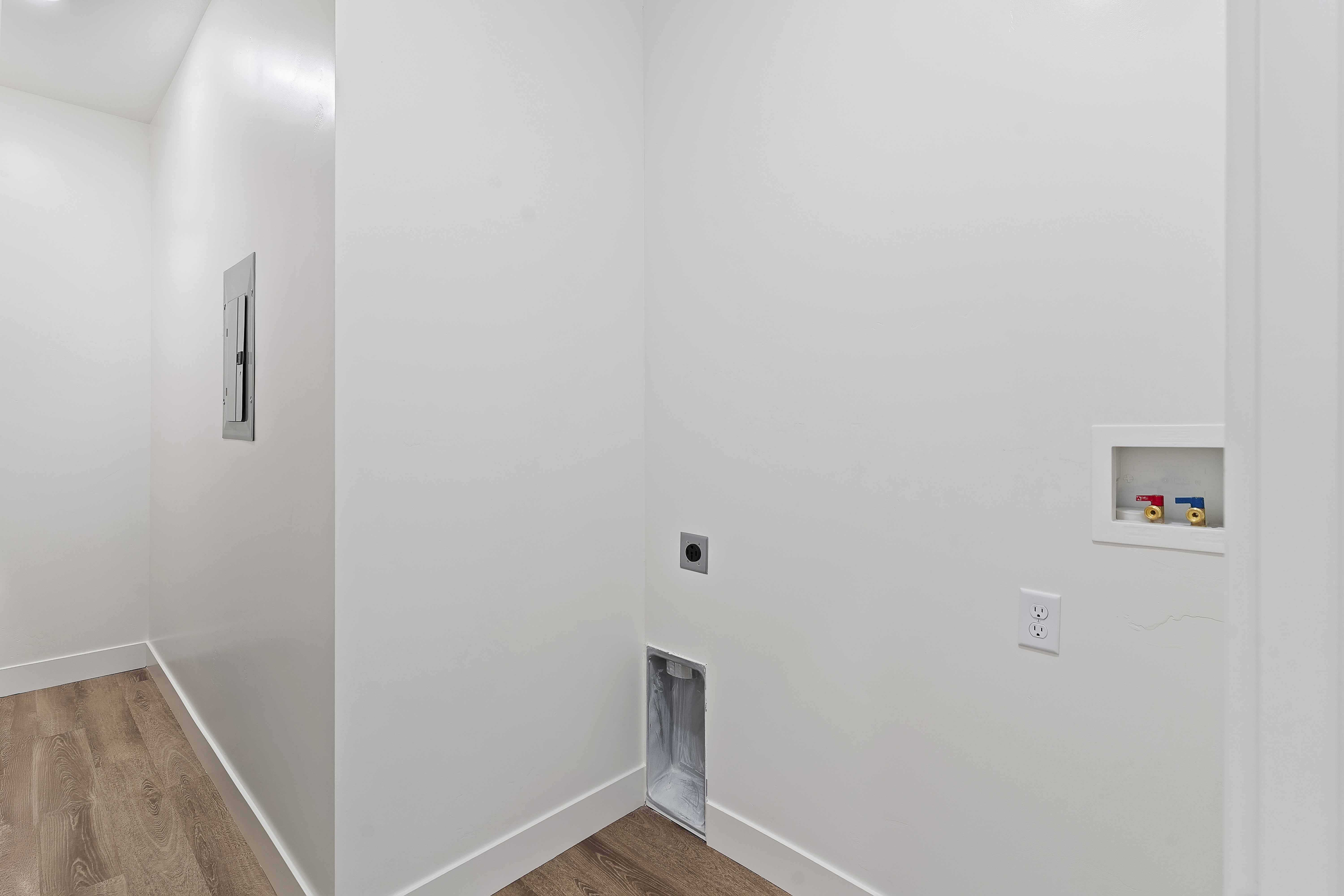 Dedicated laundry area featuring wood-finish flooring, white walls, and bright baseboards