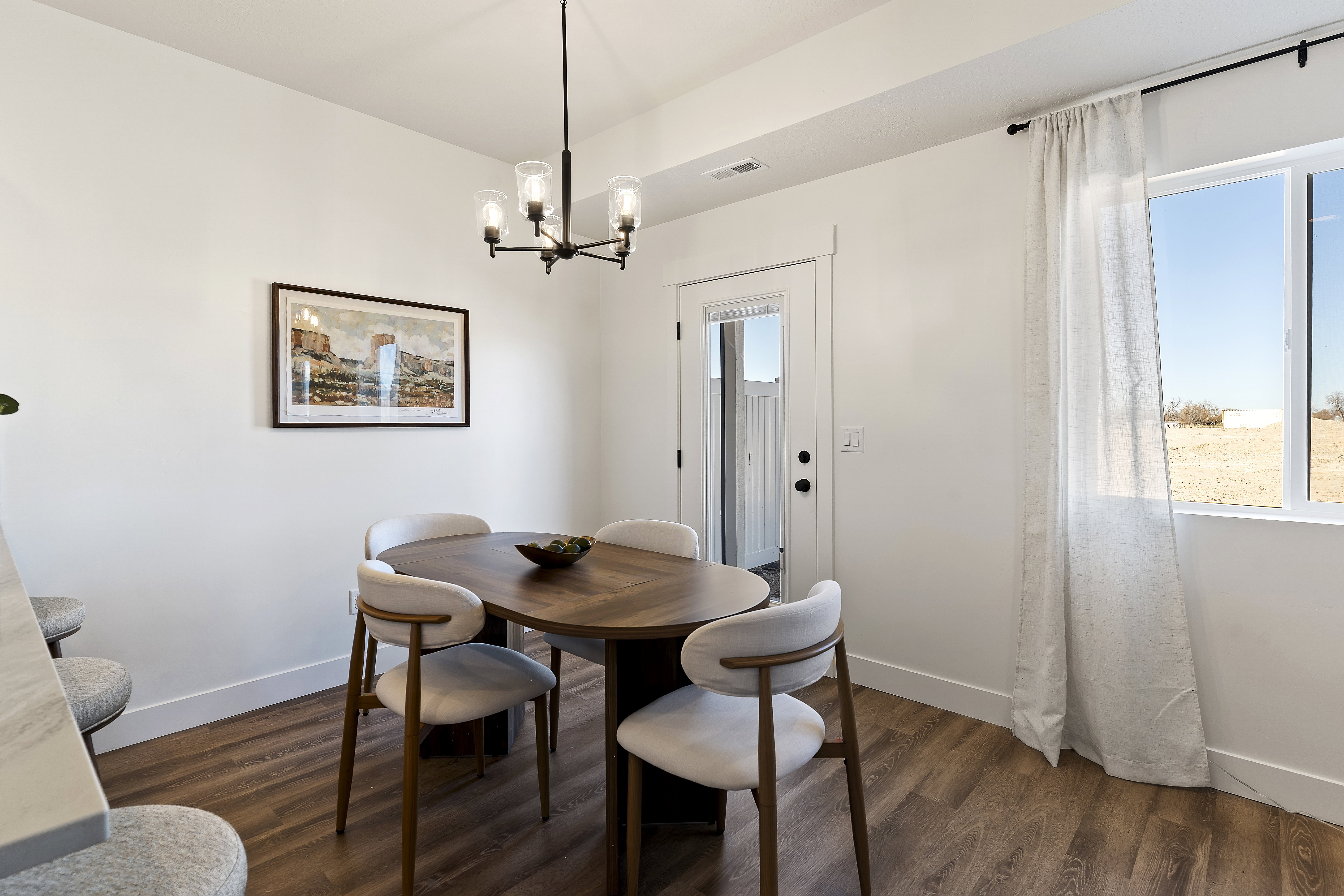 Dining area featuring wood-finish flooring, a contemporary chandelier, and a white egress door