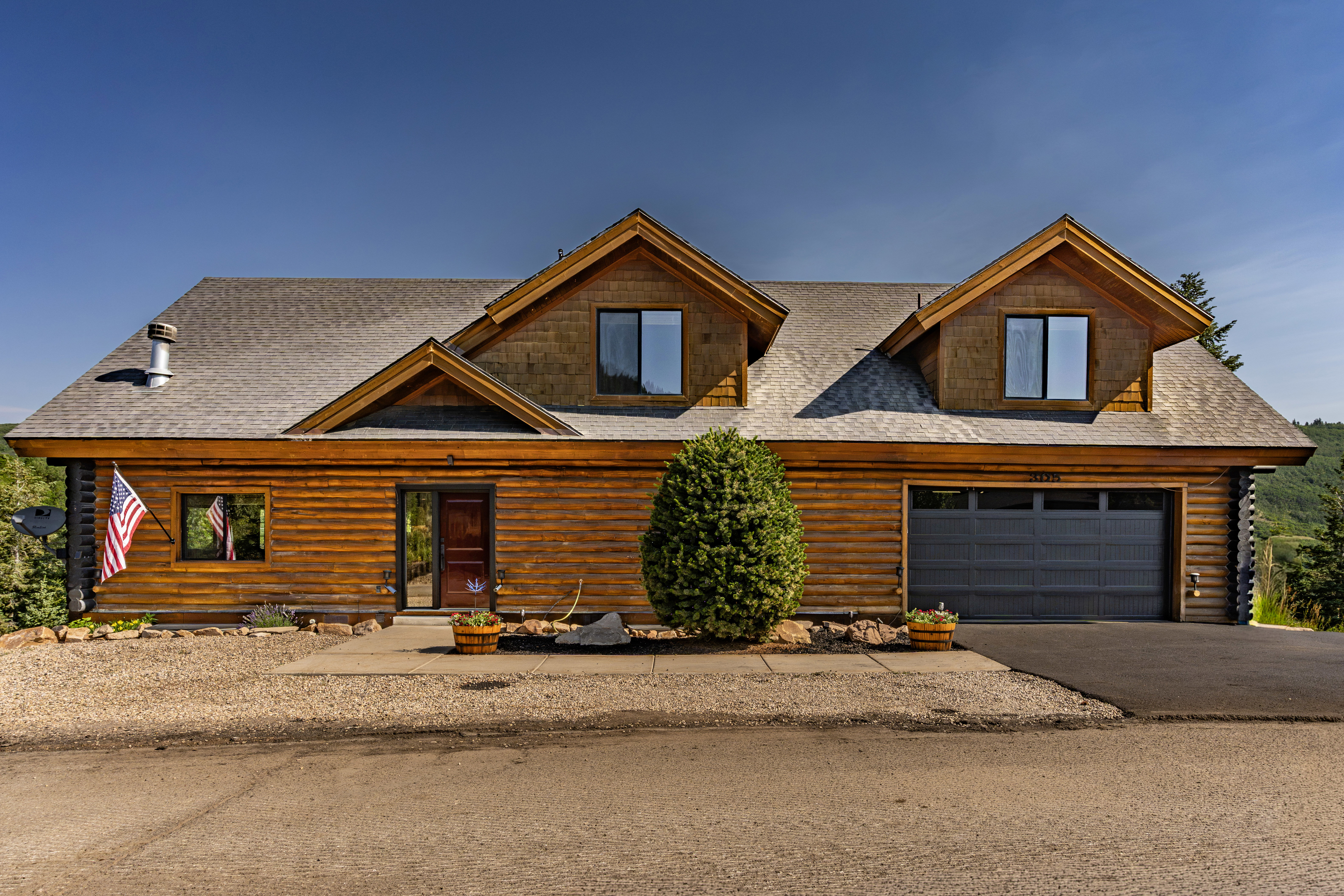 Log cabin-style exterior with a dark shingle roof and two prominent dormer windows