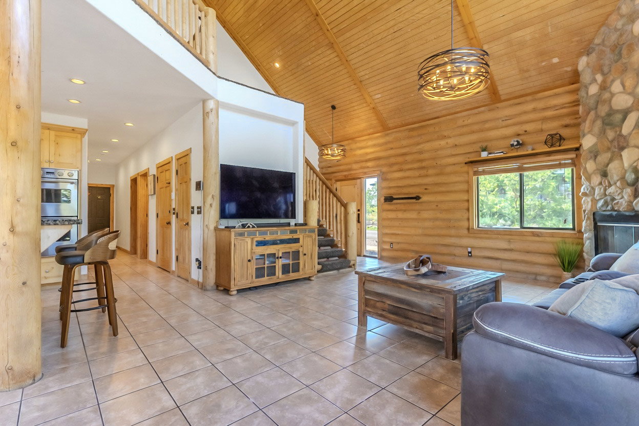 Spacious interior featuring a vaulted wood-plank ceiling, exposed log beams, and tile flooring