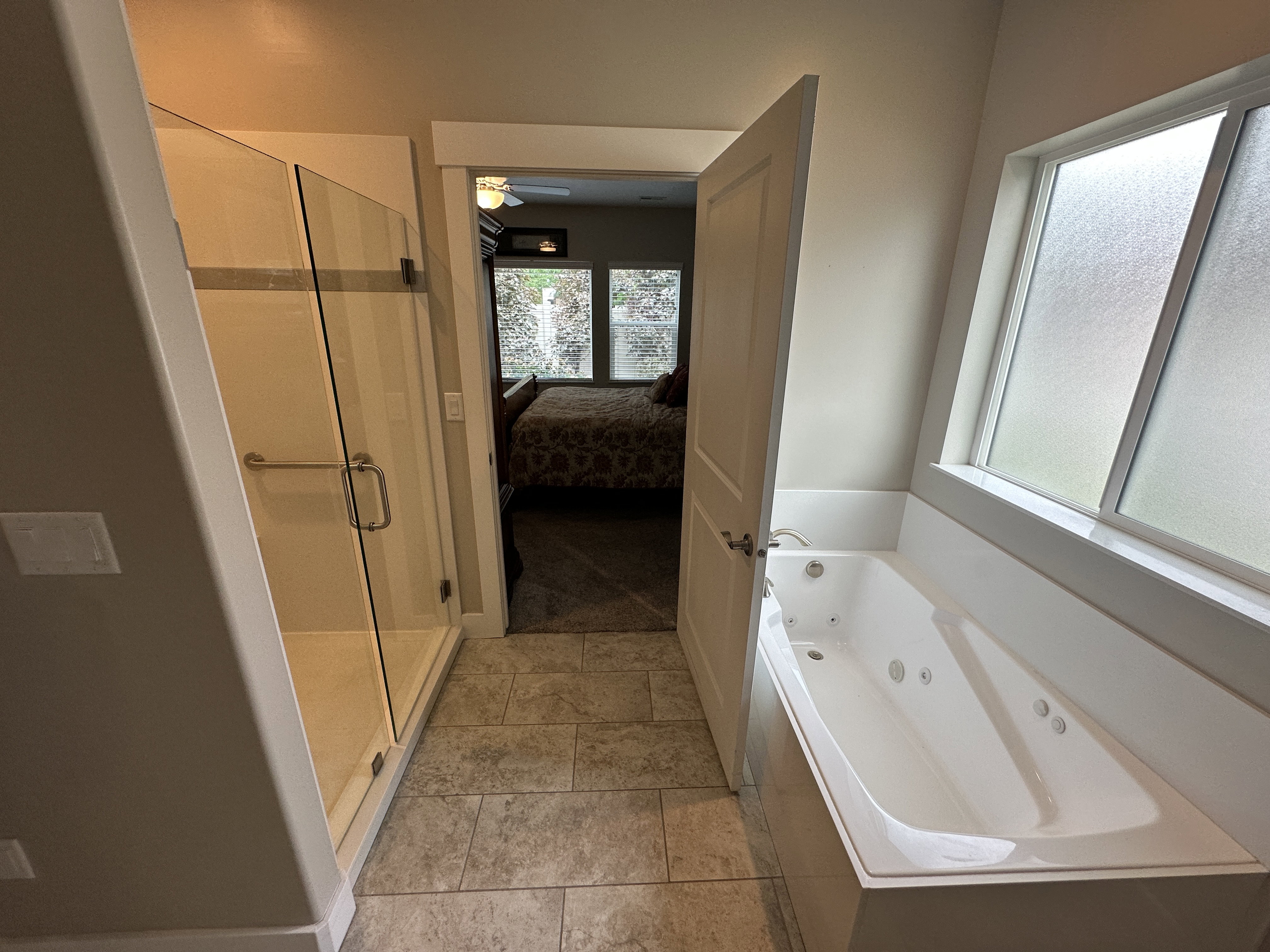 Bathroom featuring a glass-enclosed shower, built-in jetted tub, and tile flooring