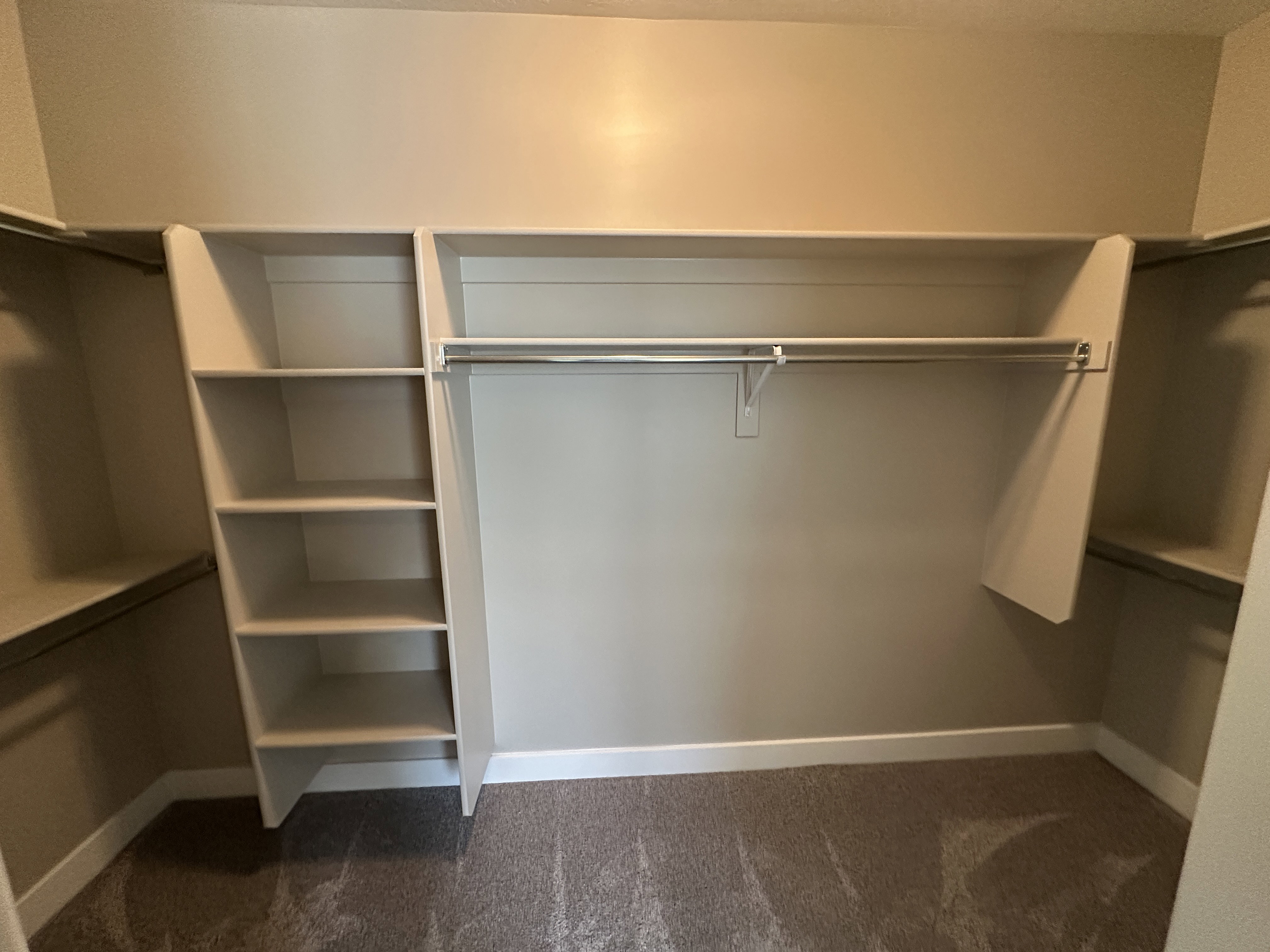 Spacious walk-in closet featuring built-in shelving, multiple hanging rods, and plush carpeting
