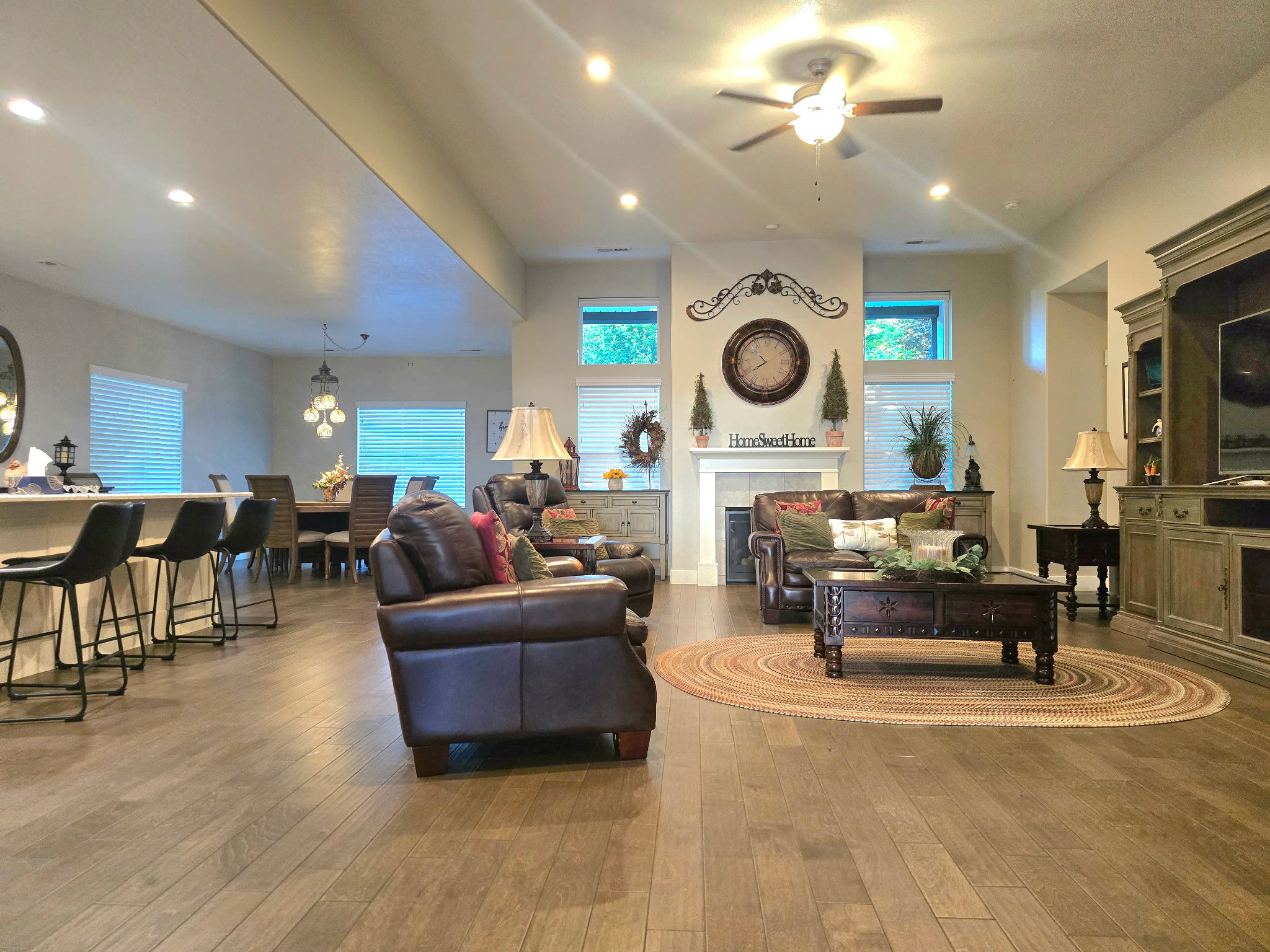 Spacious living area featuring wood-finish flooring, a fireplace with a white mantel, and ceiling fan