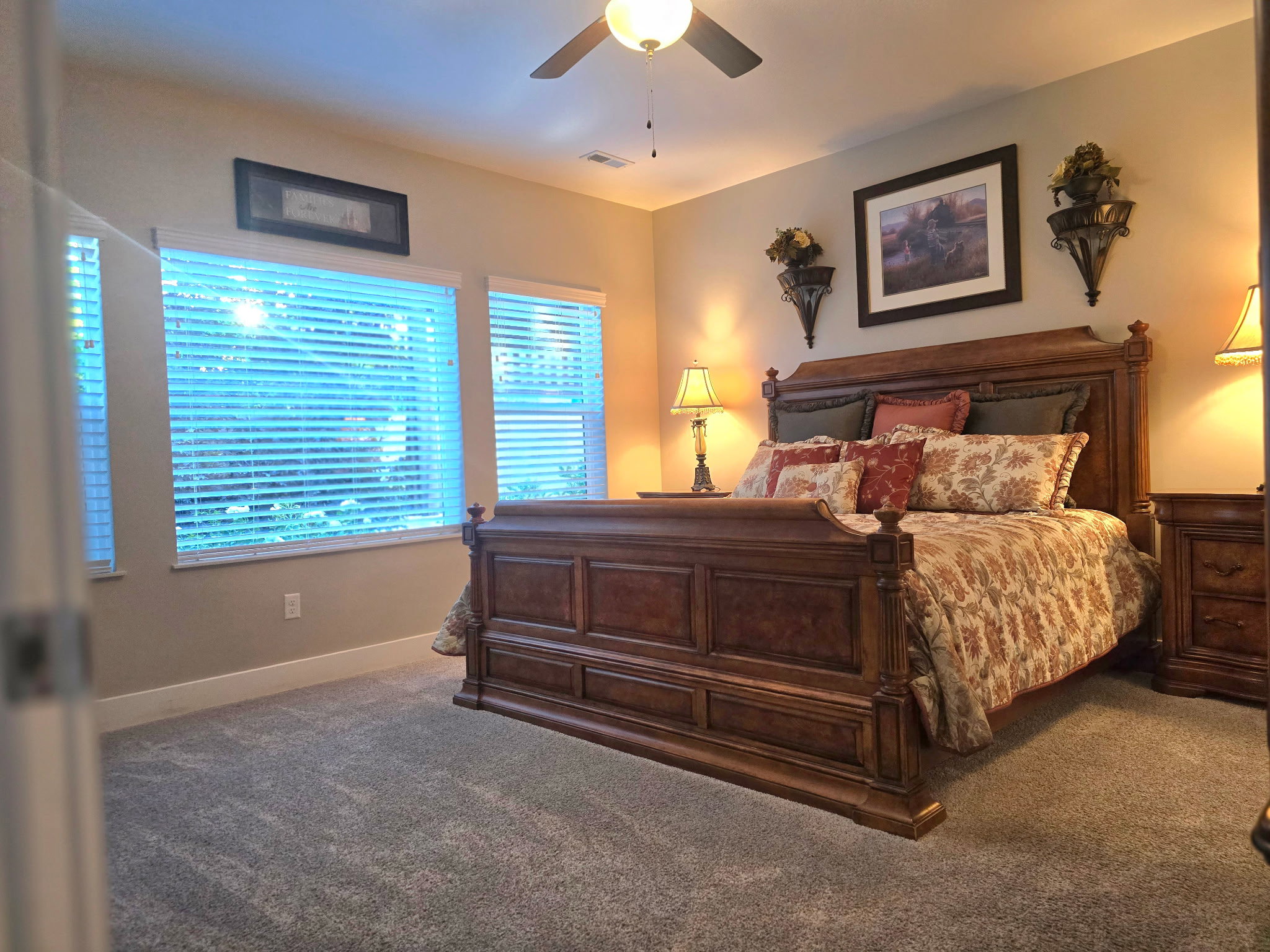 Carpeted bedroom featuring multiple windows with blinds, a ceiling fan with integrated lighting, and neutral wall tones
