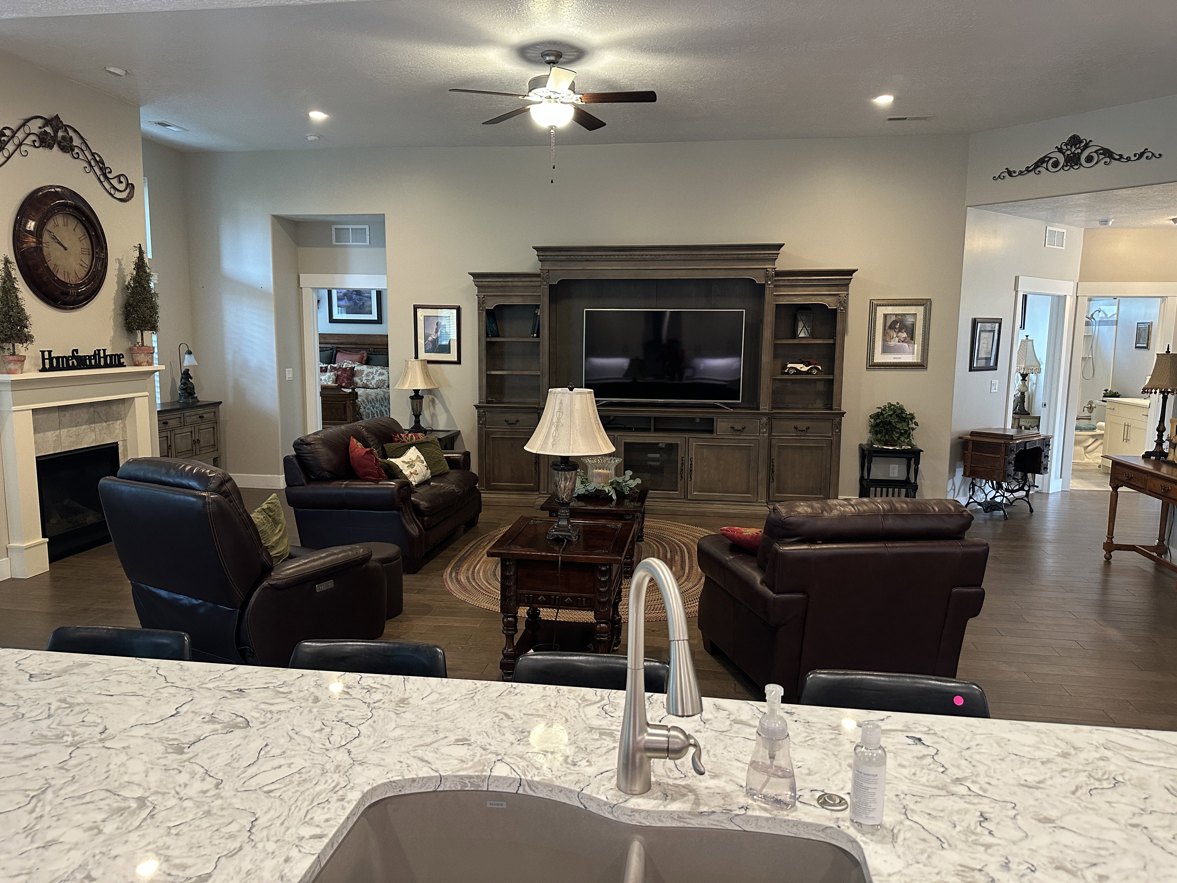 Spacious living area featuring wood-finish flooring, a built-in media console, a fireplace with a mantel, and recessed lighting