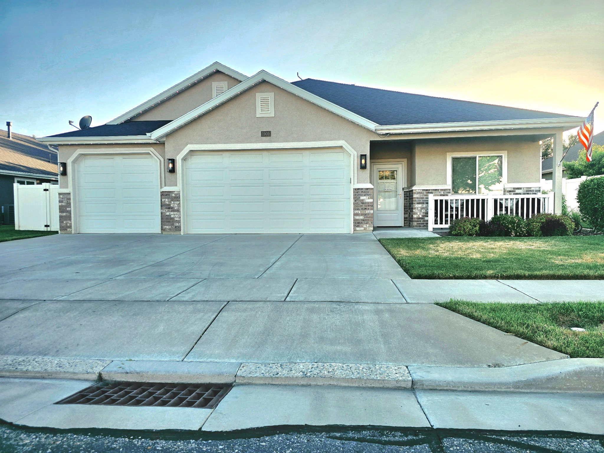 Two-car garage with concrete driveway and a covered front porch featuring white railings