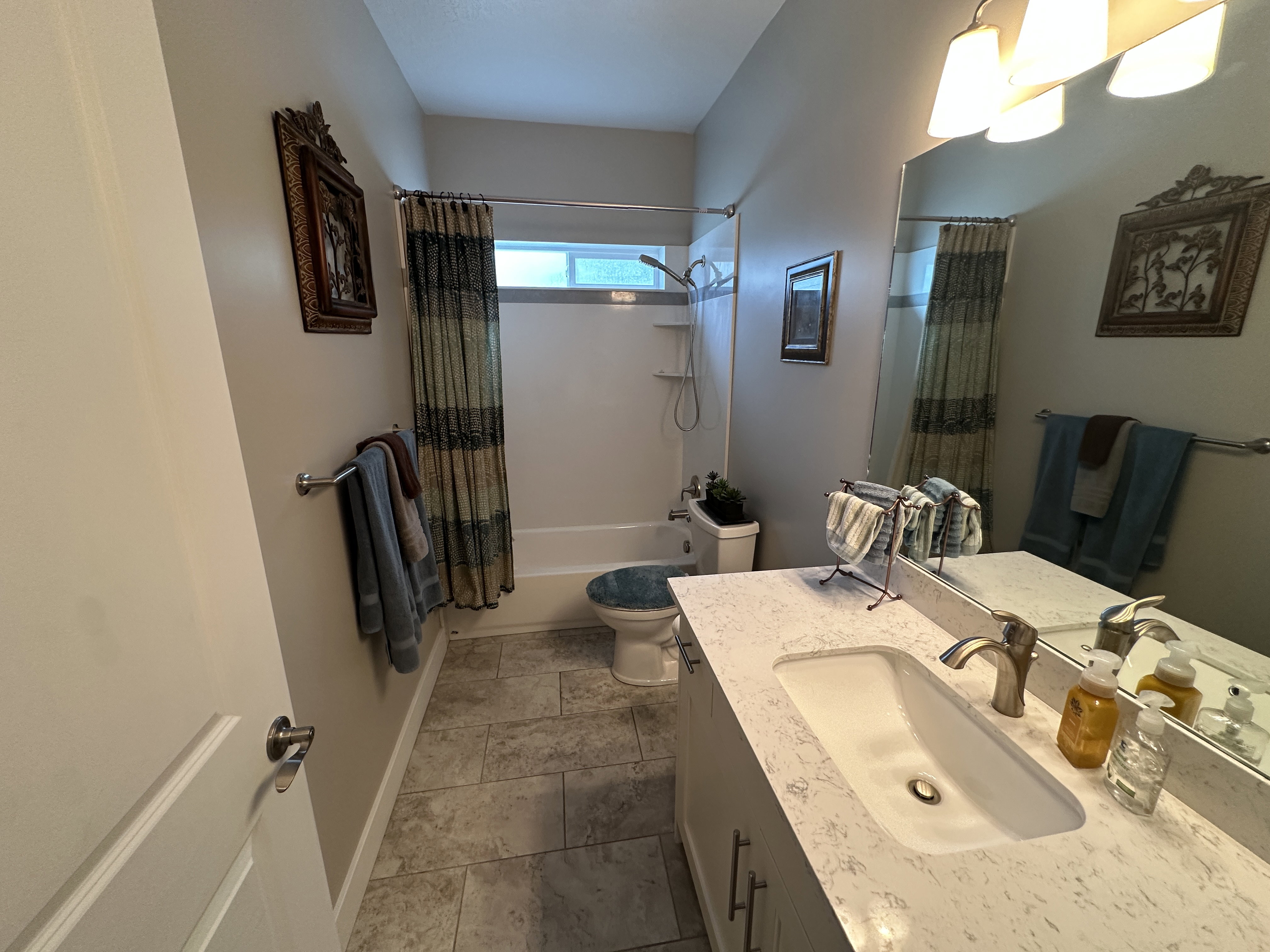 Bathroom featuring a vanity with an integrated sink, a large wall-mounted mirror, and overhead lighting