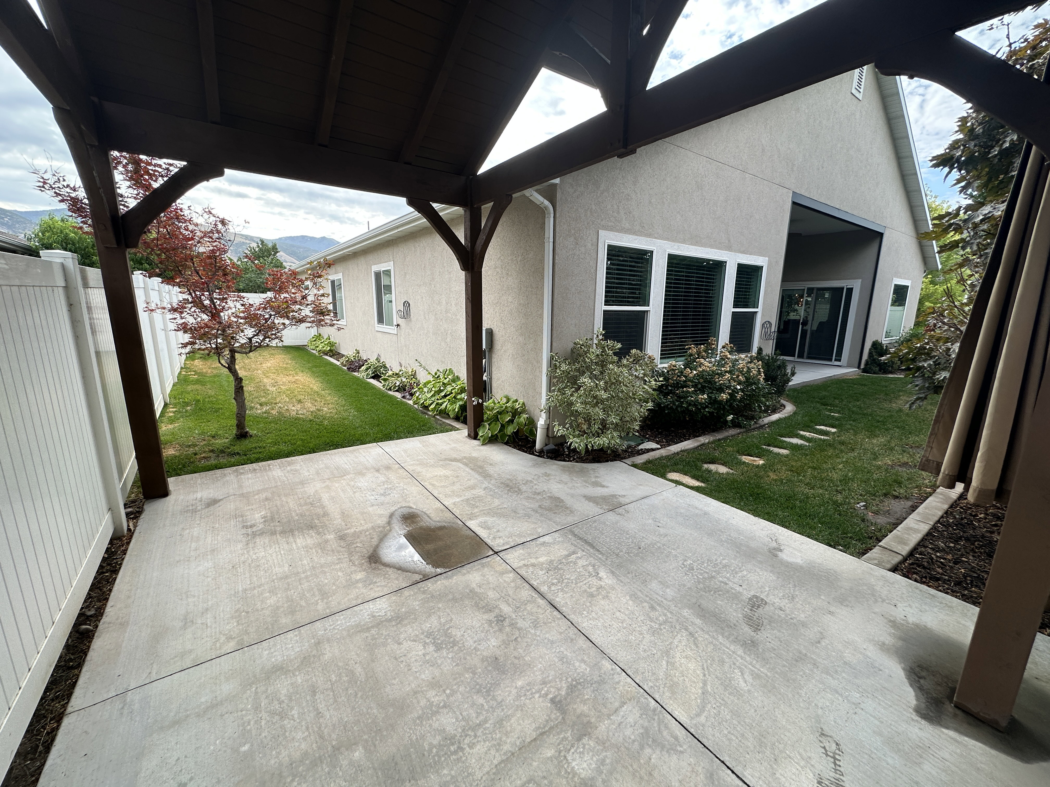 Covered concrete patio extending to a grass lawn with stepping stones