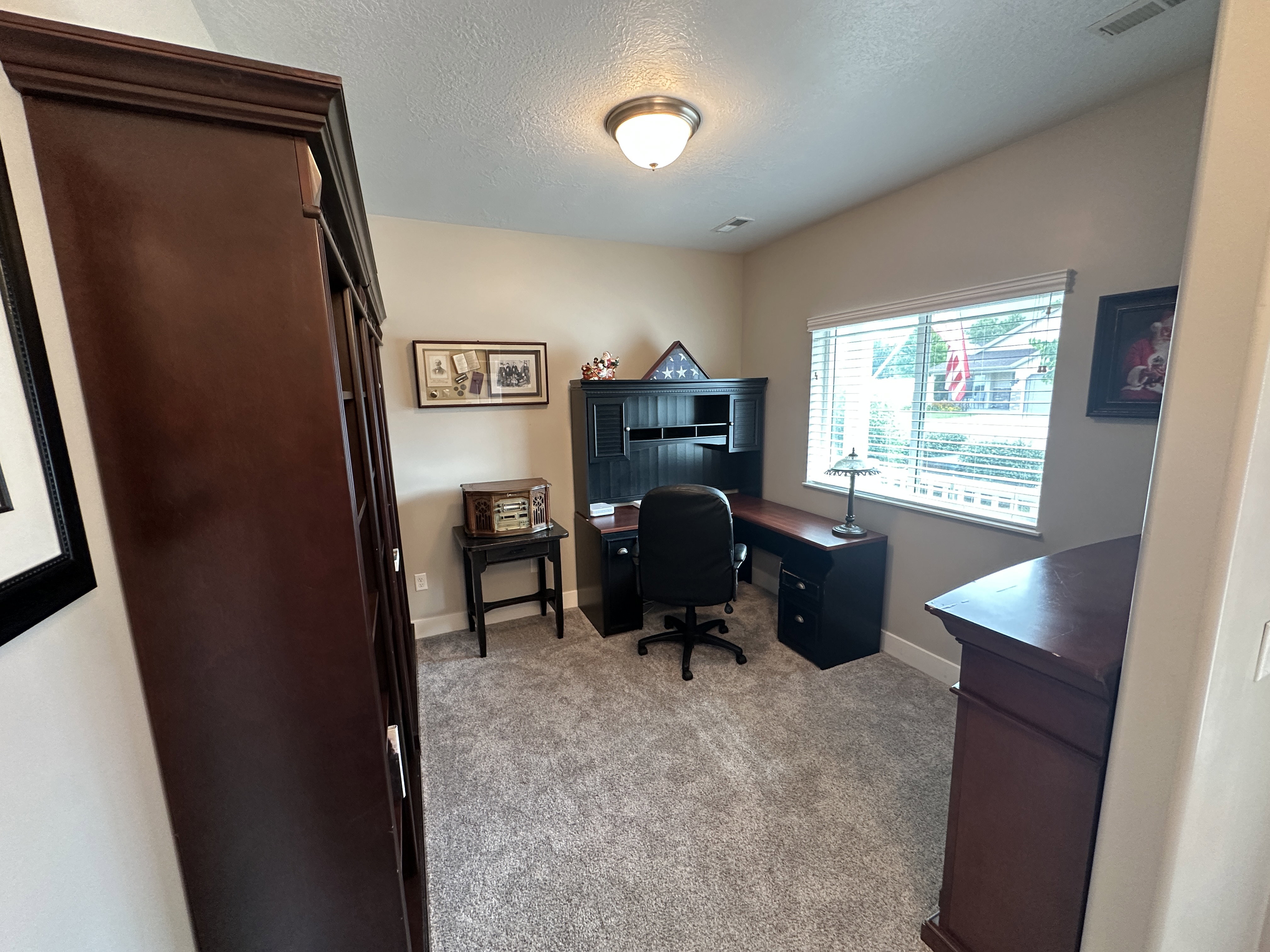 Dedicated office space featuring plush carpeting and a large window with blinds