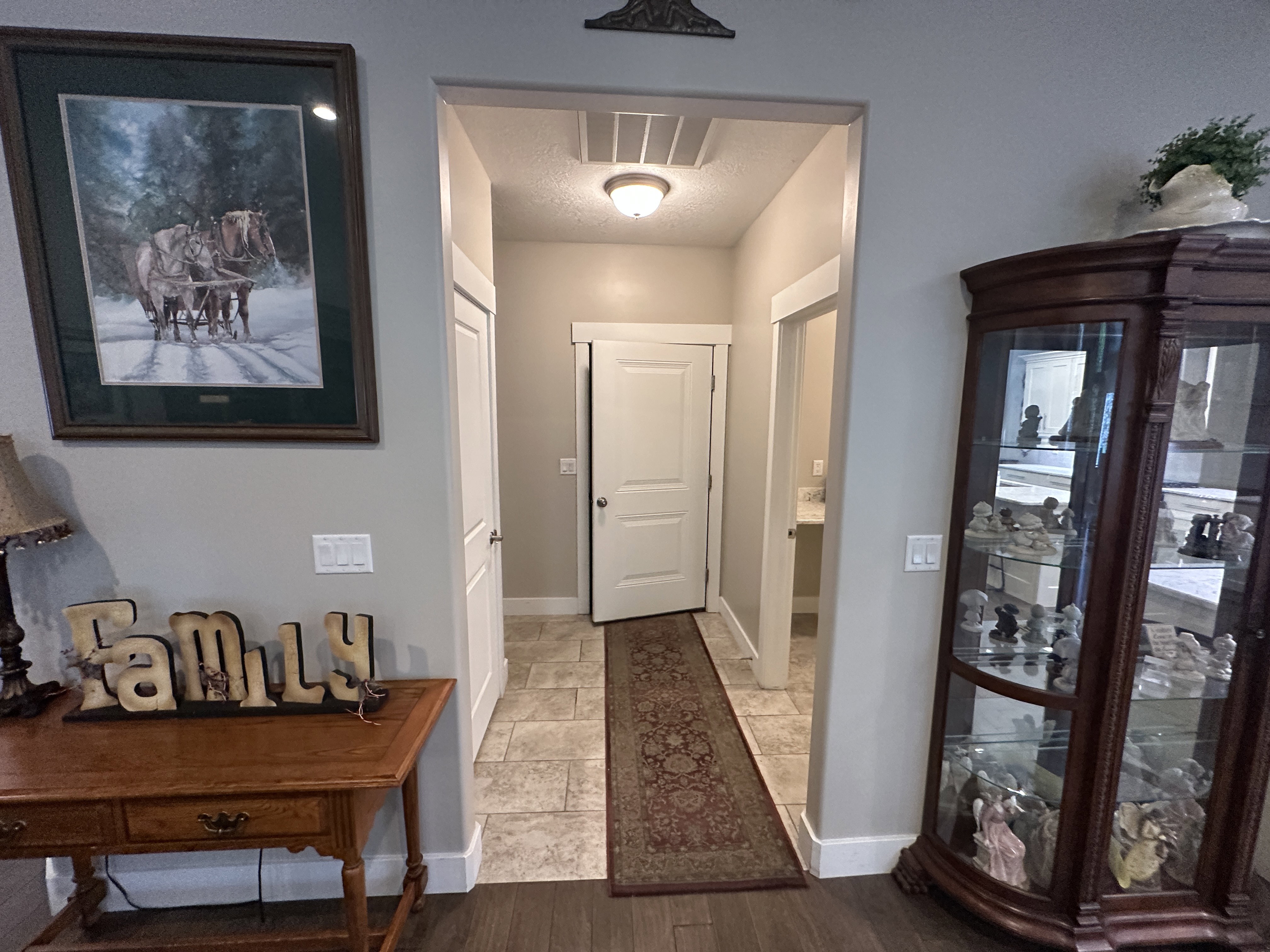 Hallway featuring wood-finish flooring, light tan walls, and white baseboards