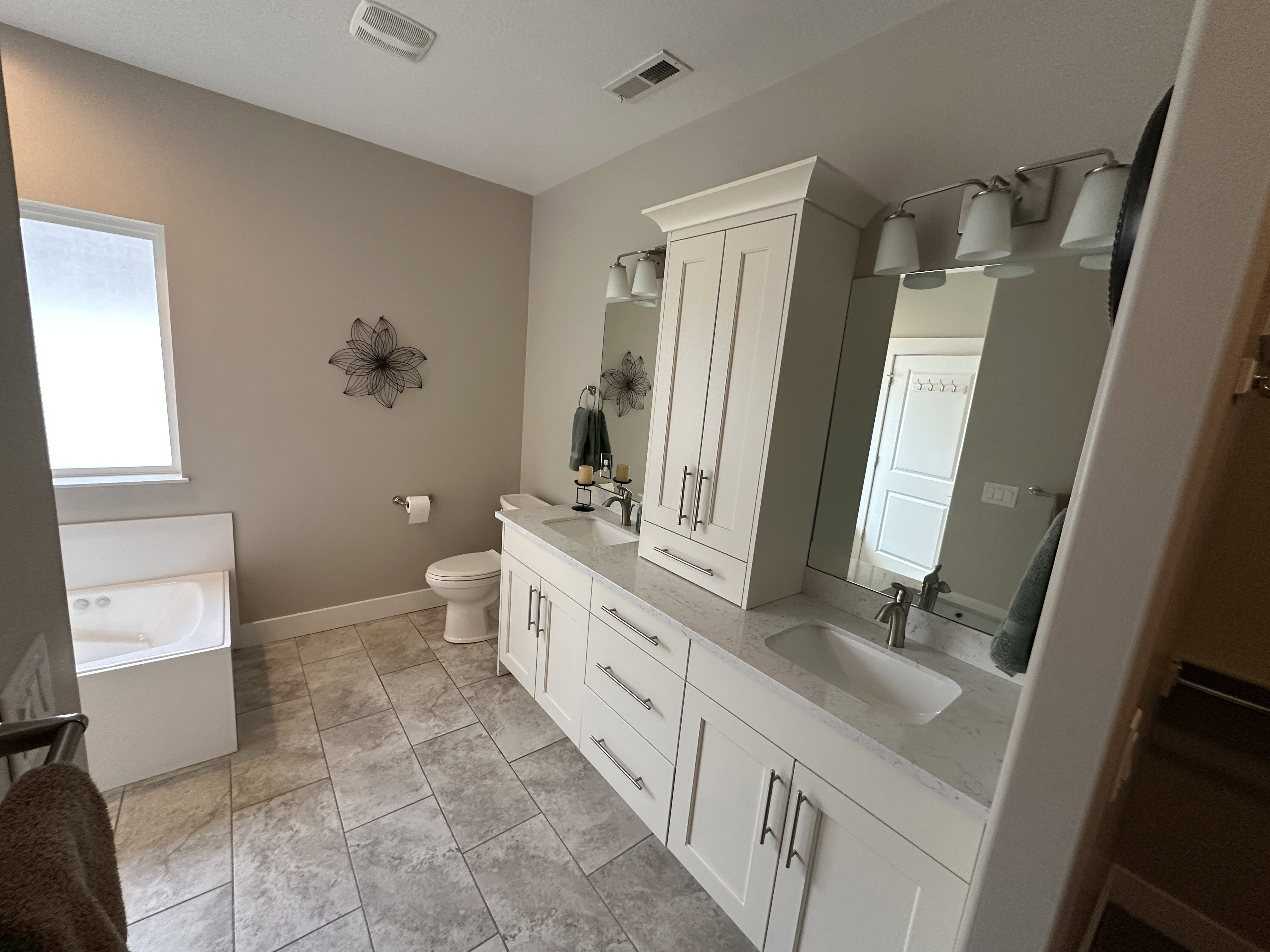 Double vanity featuring white cabinetry, integrated sinks, and polished chrome fixtures