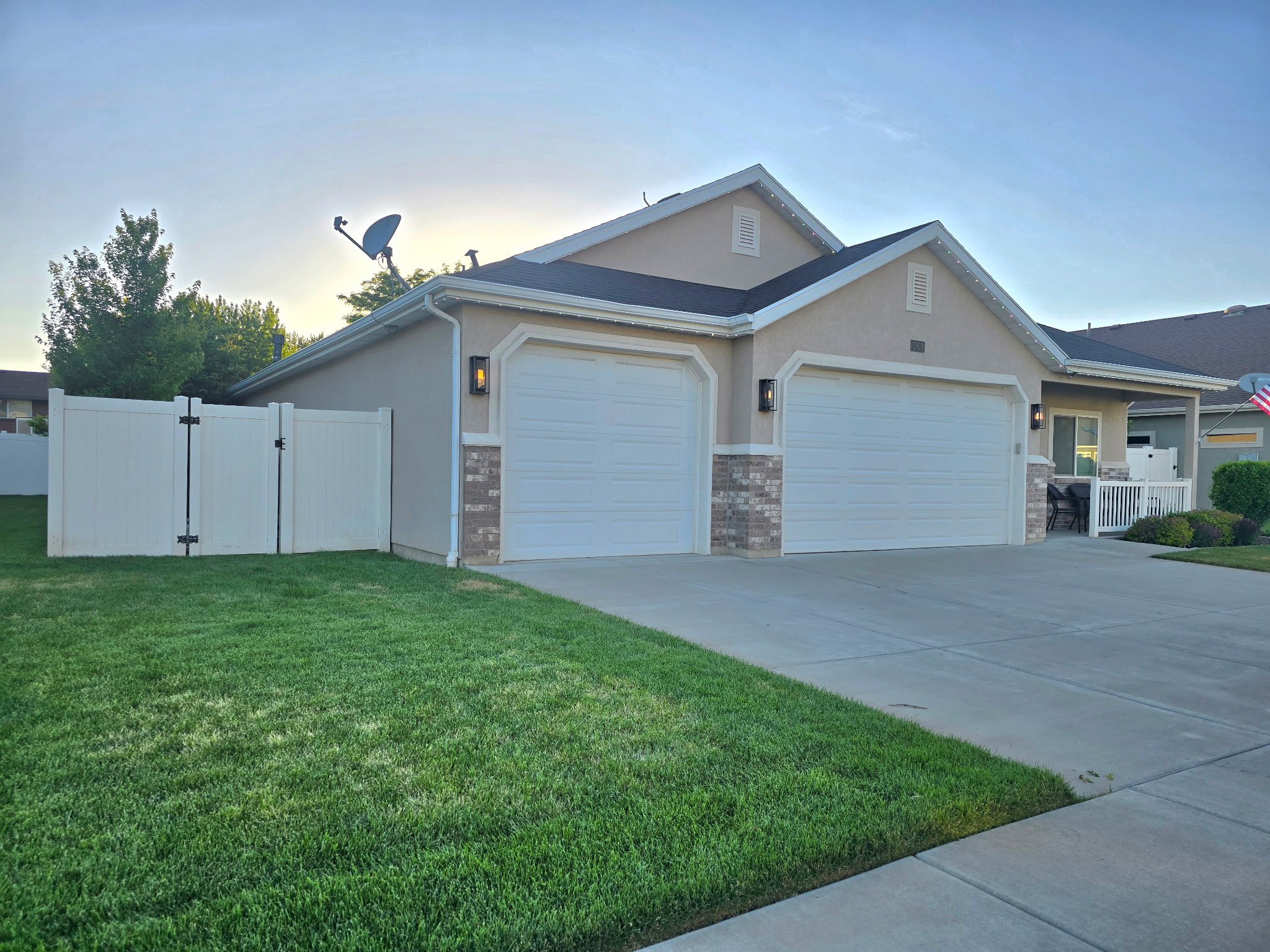Stucco exterior featuring dual garage doors, brick veneer accents, and an attached front porch with white railings