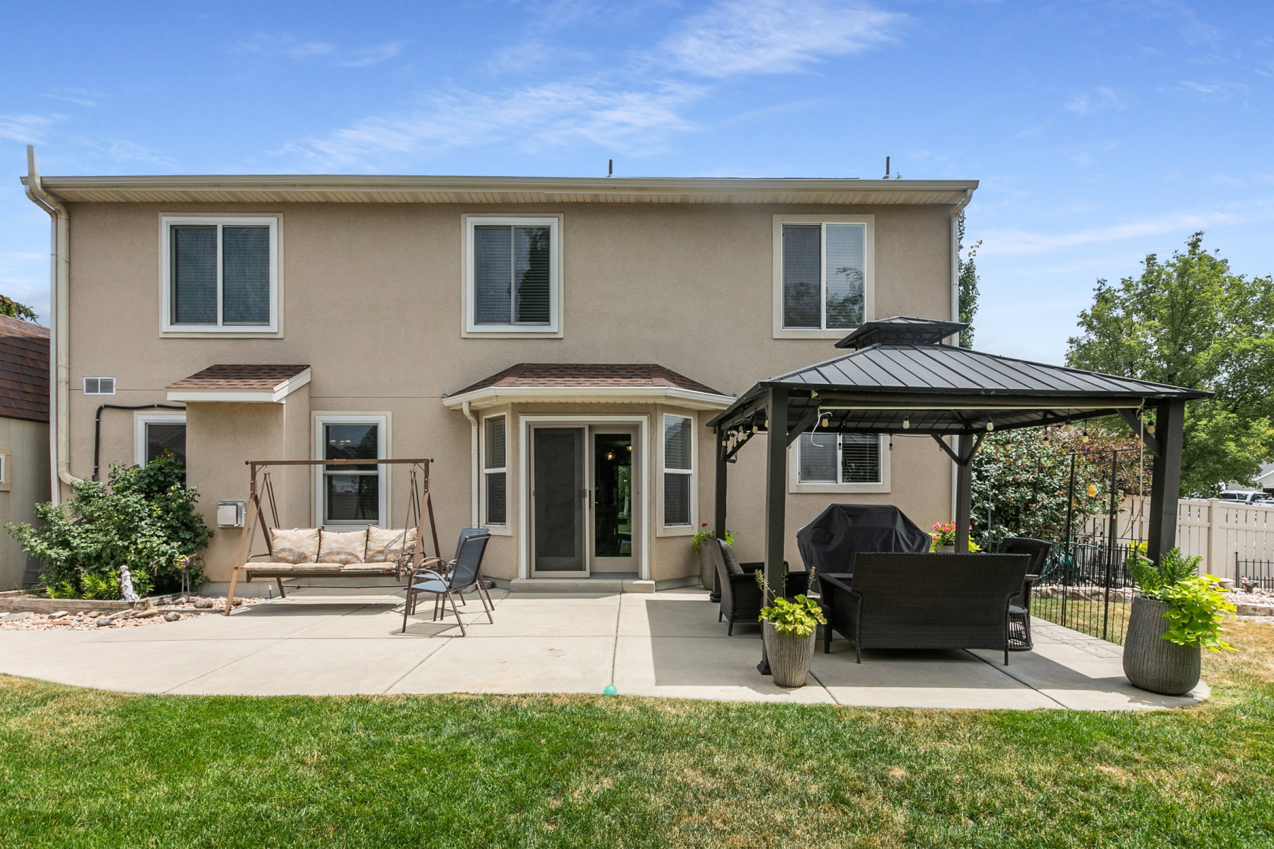 Rear exterior featuring a spacious concrete patio, manicured lawn, and new French  glass doors