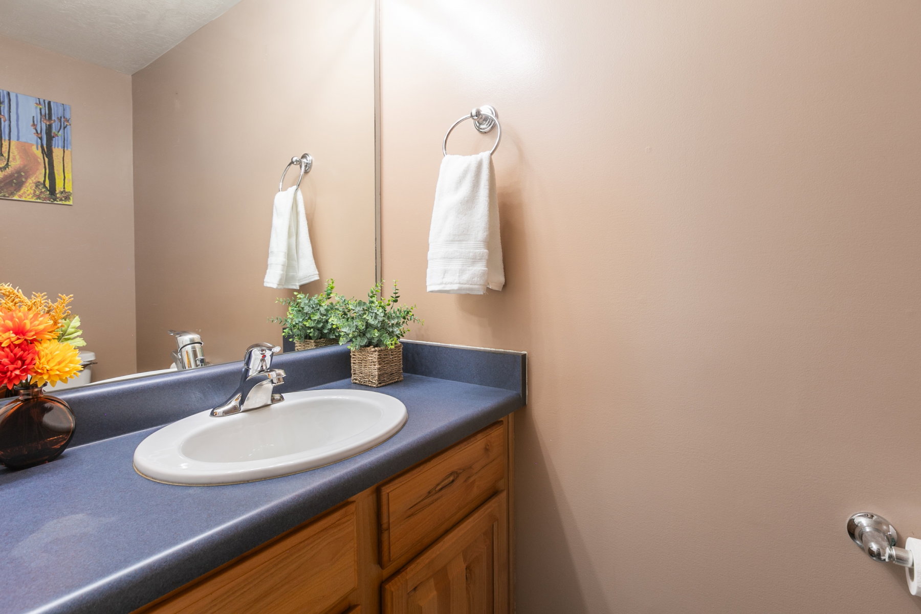 Vanity with an integrated oval sink and chrome faucet, complemented by a large wall-mounted mirror