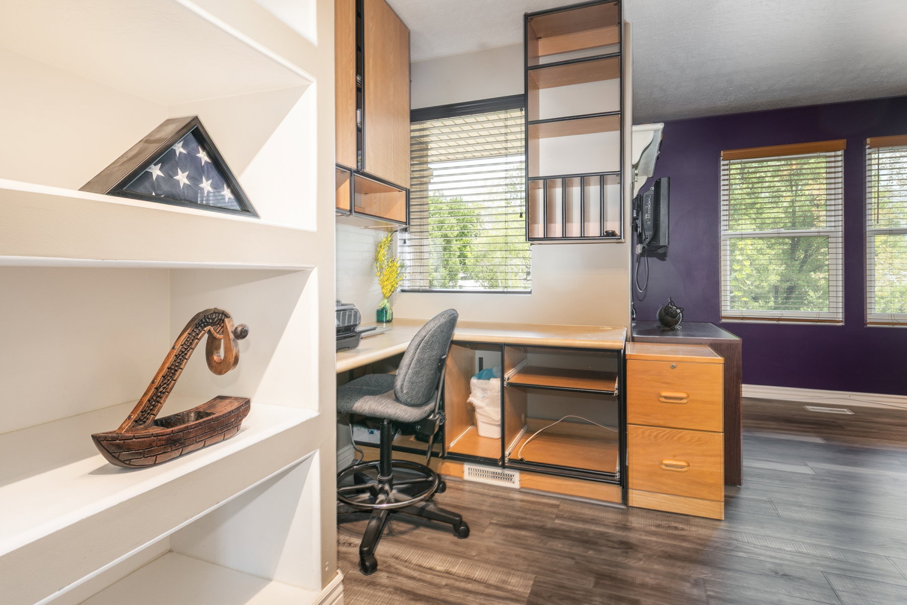 Built-in shelving and desk area featuring overhead cabinetry, wall-mounted shelving, and wood-finish flooring
