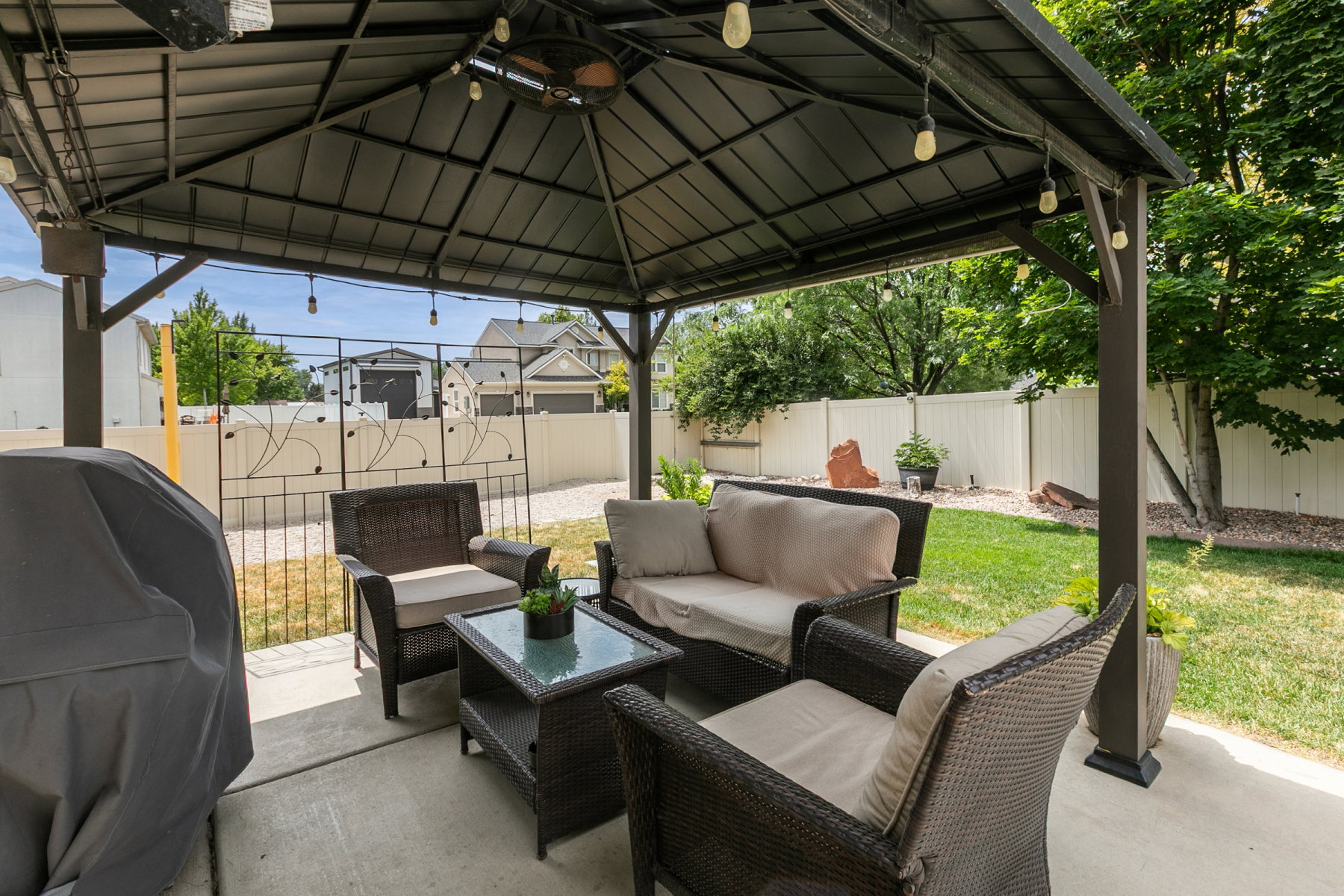 Expansive patio featuring a metal gazebo with integrated string lights and a ceiling fan