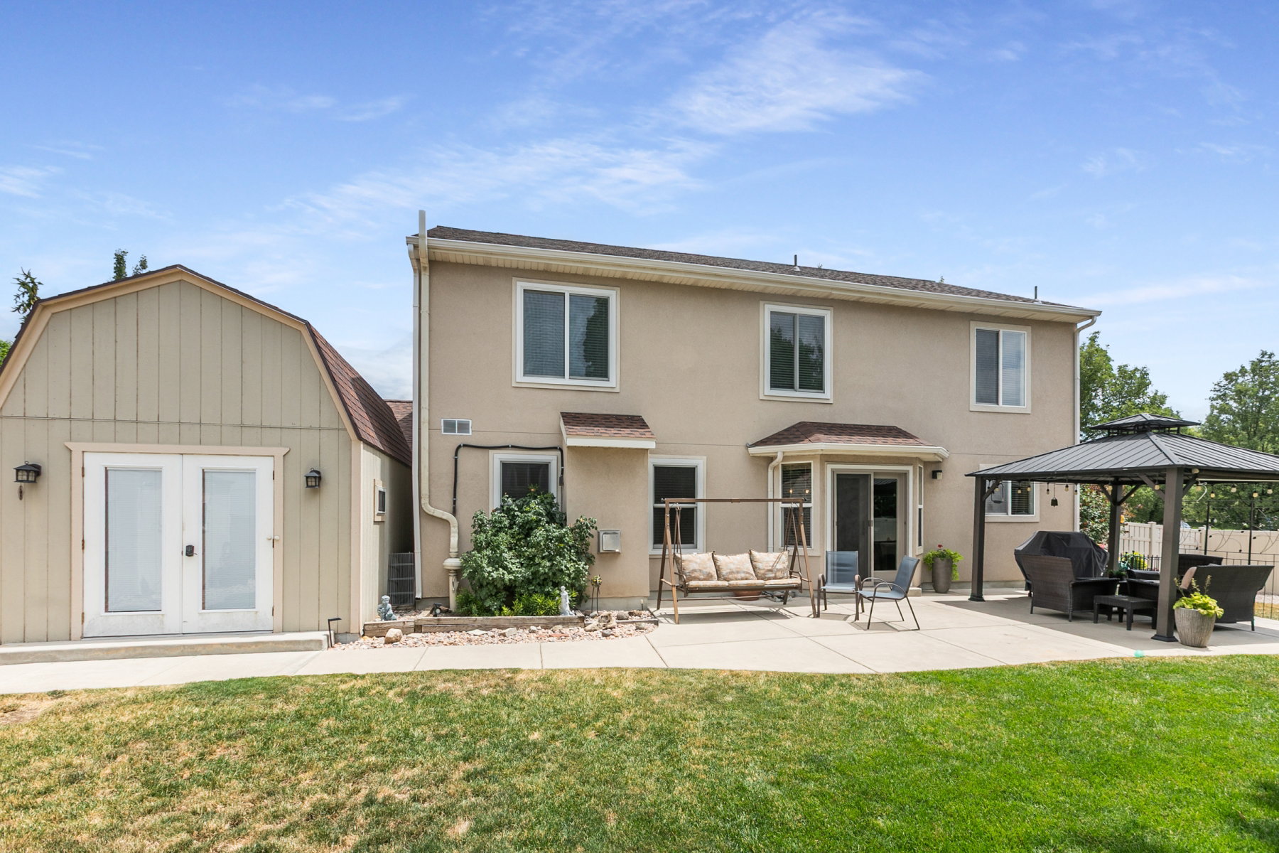 Attached Bonus Room, separate entrance, expansive backyard featuring a large concrete patio, a detached auxiliary structure with double doors, and a two-story home with a stucco exterior