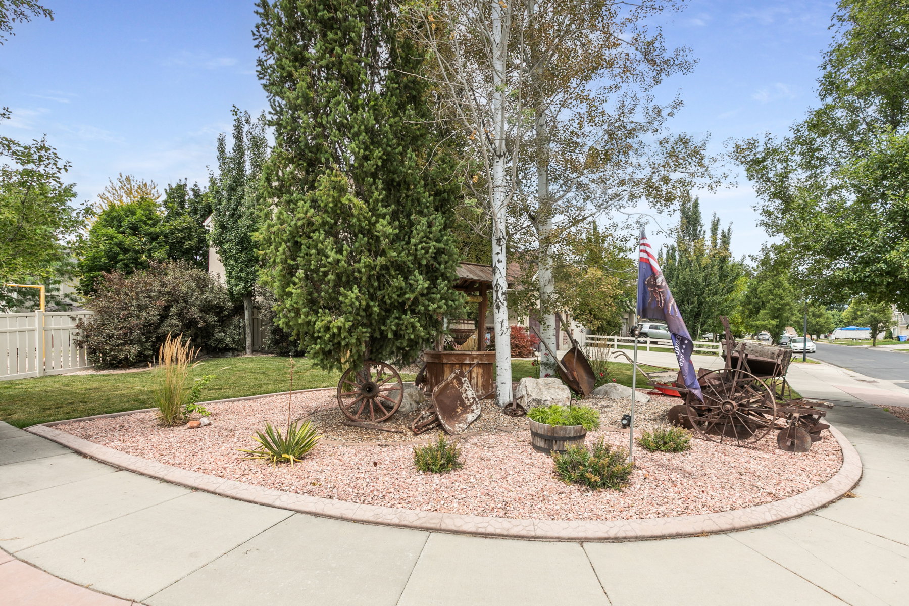 Front yard landscaping featuring a gravel bed, mature trees, and a concrete border
