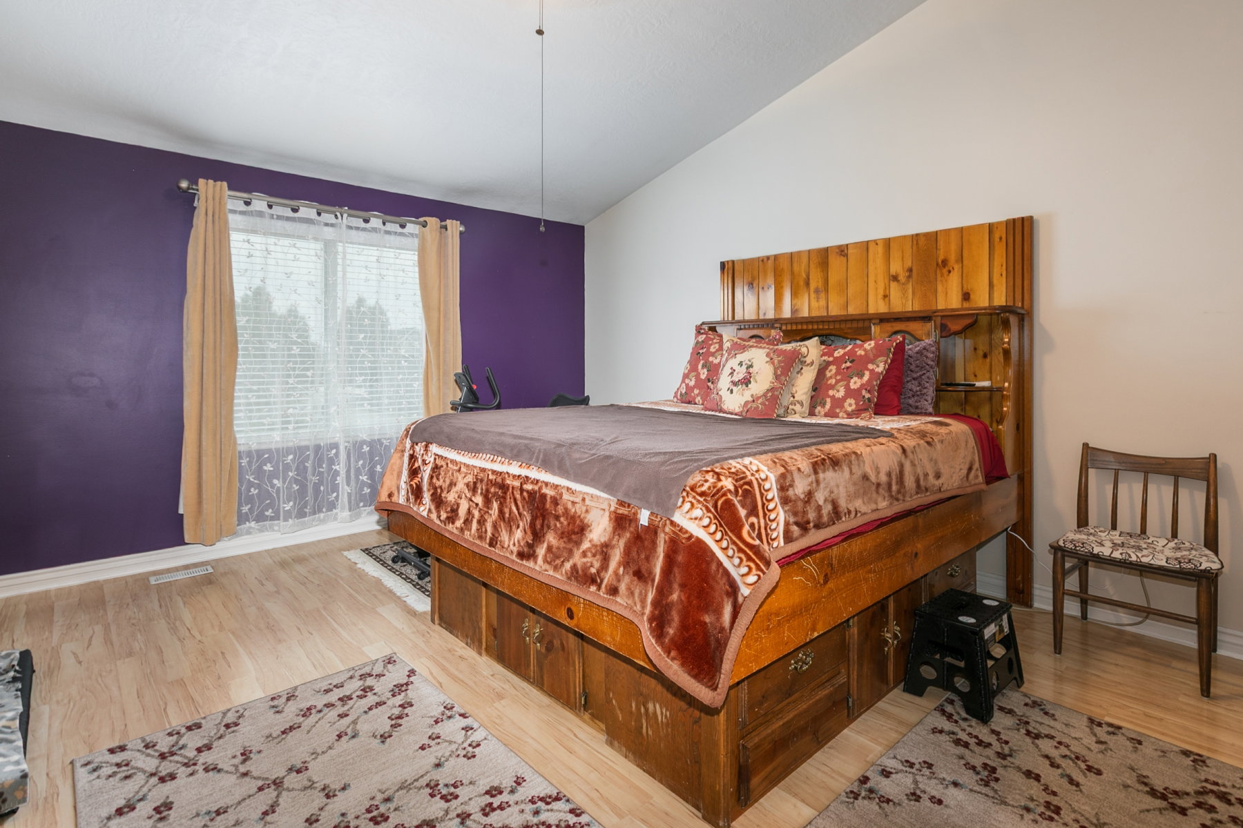 Spacious primary bedroom featuring wood-finish flooring and a large window with blinds