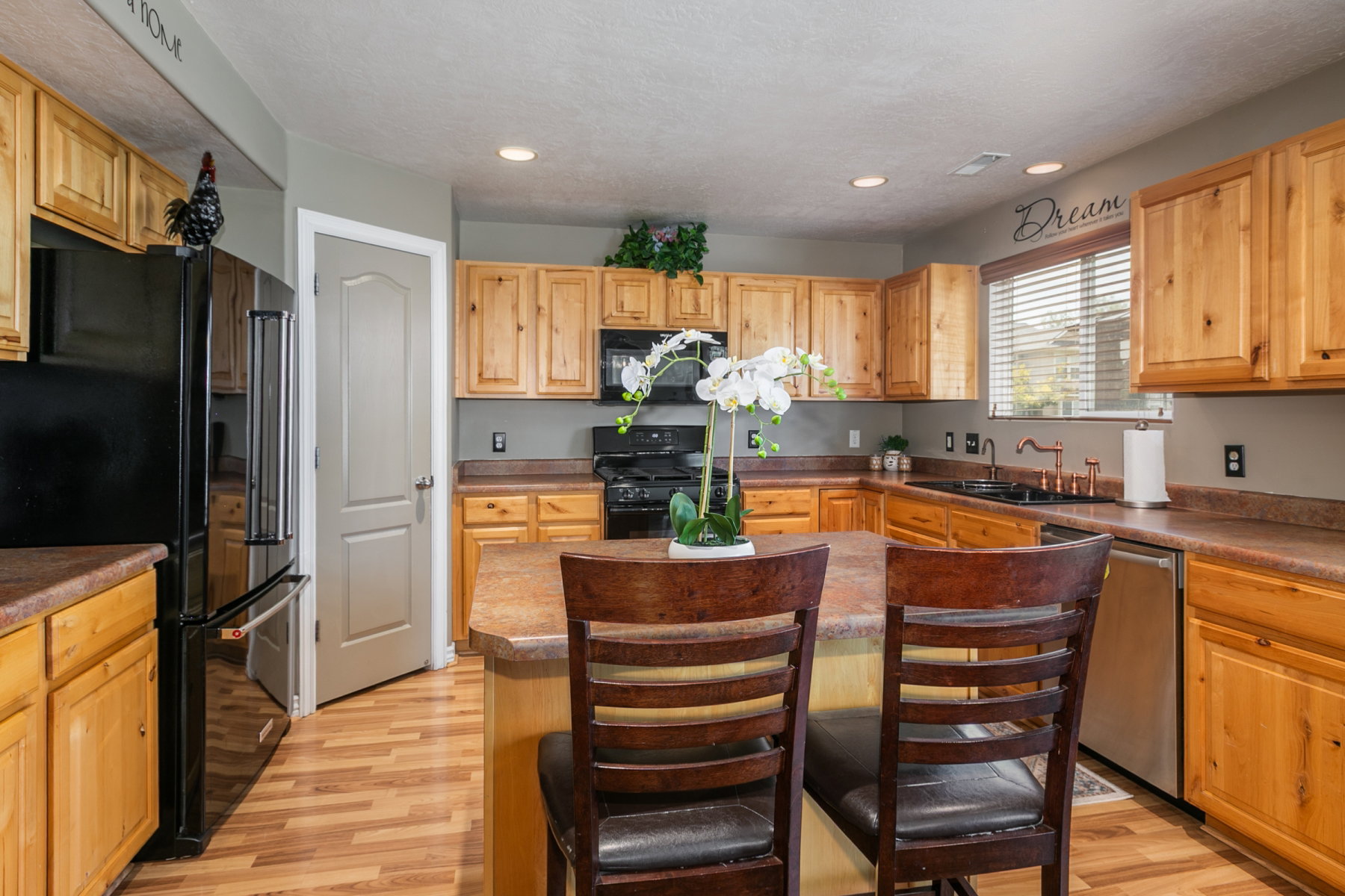 Kitchen featuring a central island with island countertop seating, light wood cabinetry, wood-finish flooring, recessed lighting, and corner pantry