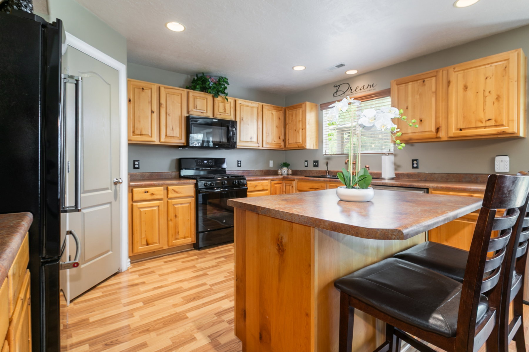Kitchen featuring wood-finish flooring, natural wood cabinetry, and a central island with bar seating