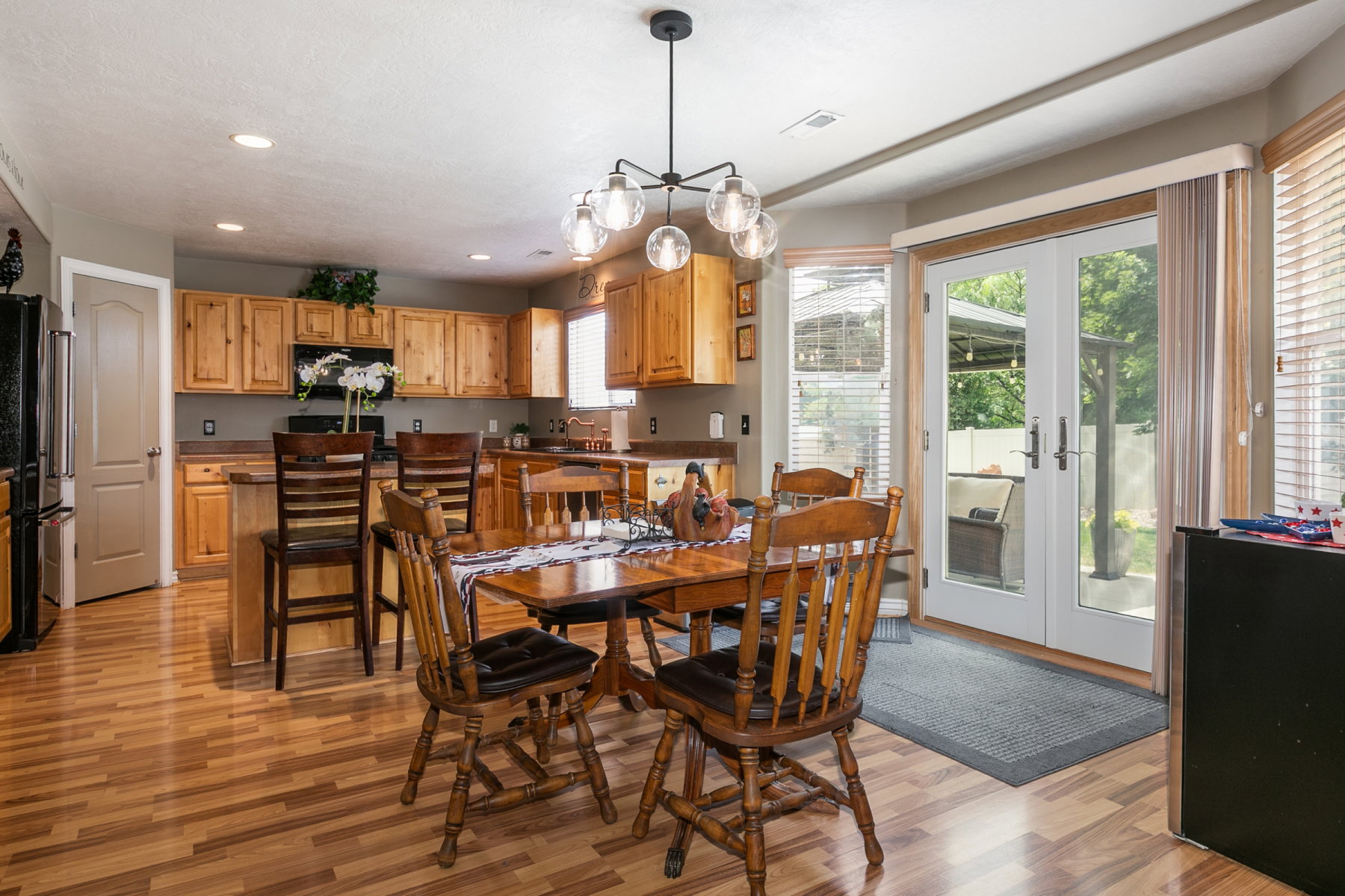 Kitchen and dining area featuring wood-finish flooring, light wood cabinetry, recessed lighting, and a modern chandelier
