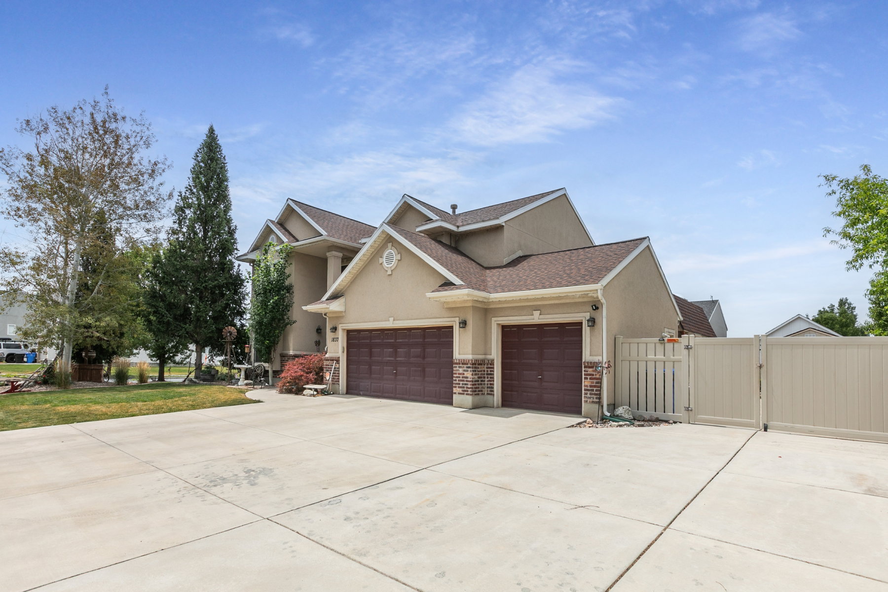 Stucco exterior home featuring a large concrete driveway with  an attached three-car garage and RV parking.
