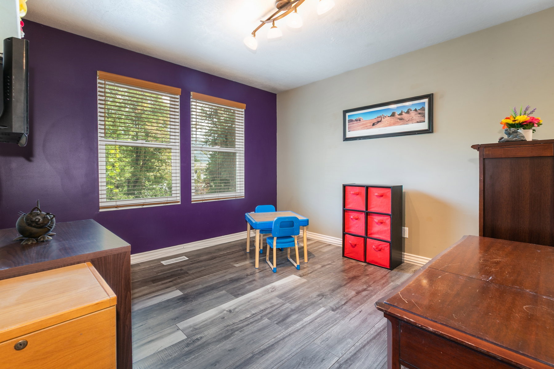 Bright interior open room featuring wood-finish flooring and two large windows with blinds
