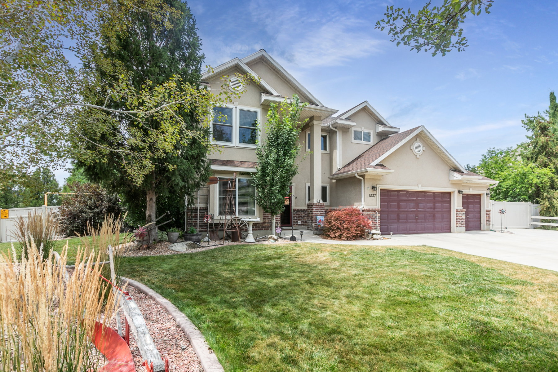 Two-story featuring a stucco exterior with stone accents, a multi-car garage with panel doors, and a concrete driveway