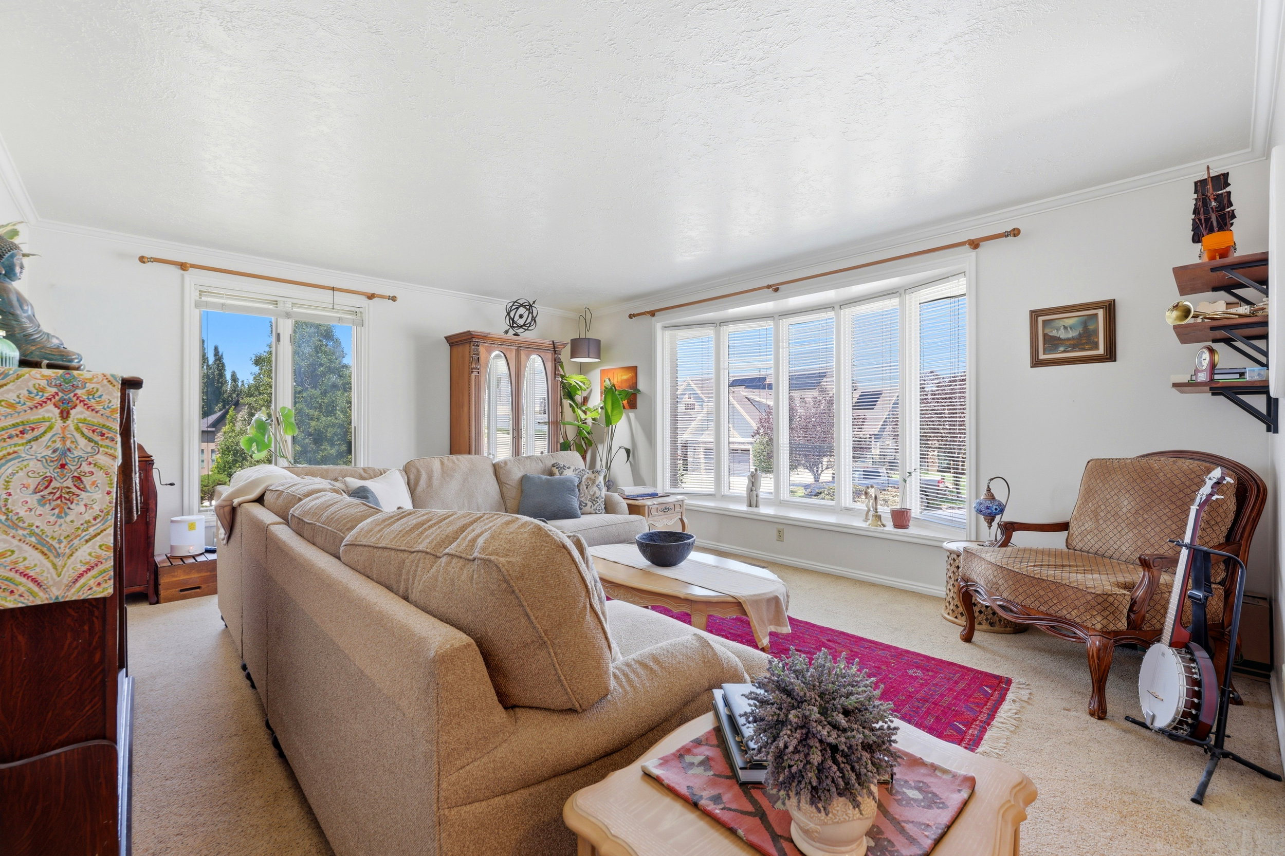 Bright living area featuring a large bay window with horizontal blinds, providing abundant natural light